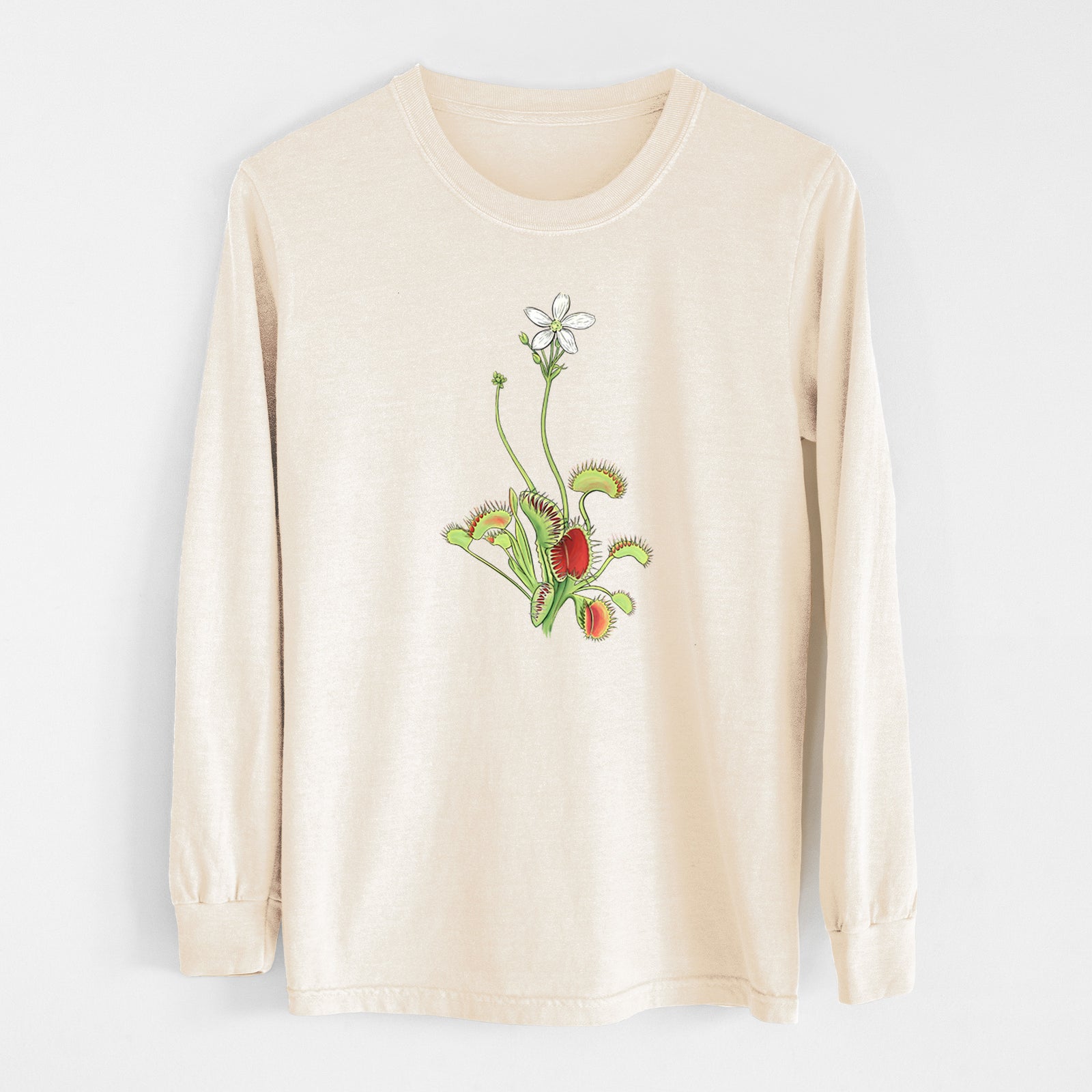 Ivory Comfort Colors long sleeve shirt laid flat, printed with a full-color illustration of a Venus flytrap plant with red traps and a small white flower.