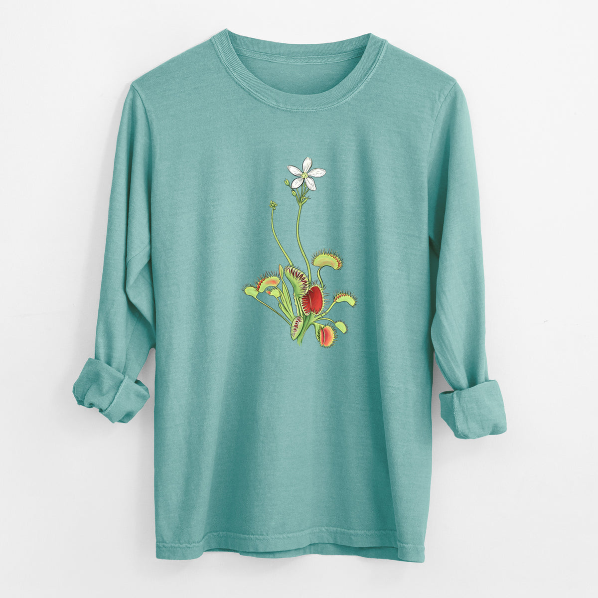 Reef green Comfort Colors long sleeve shirt laid flat with the cuffs rolled, printed with a full-color illustration of a Venus flytrap plant with red traps and a small white flower.