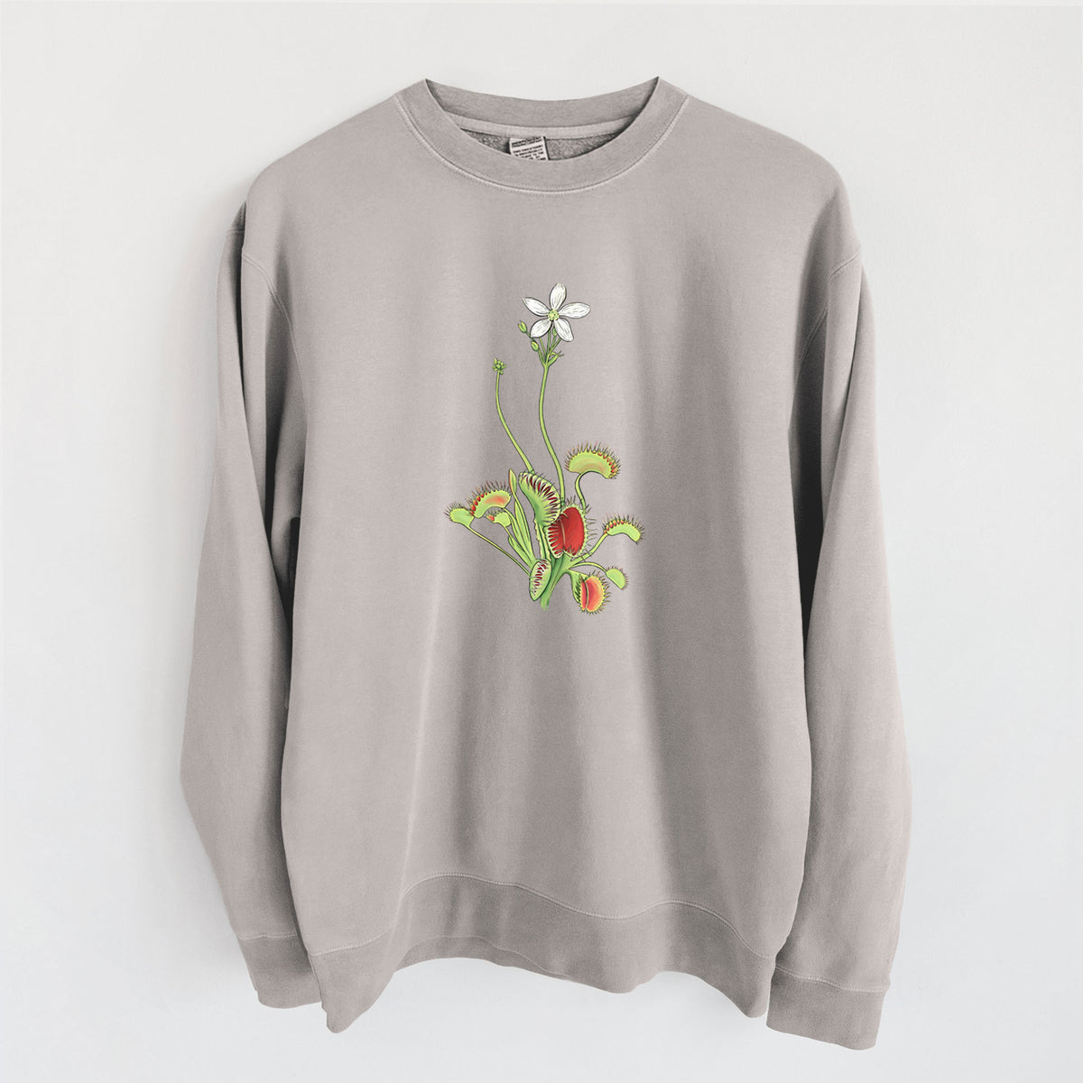 Cement grey pigment dyed crewneck sweatshirt laid flat, printed with a full-color illustration of a Venus flytrap plant with red traps and a small white flower.