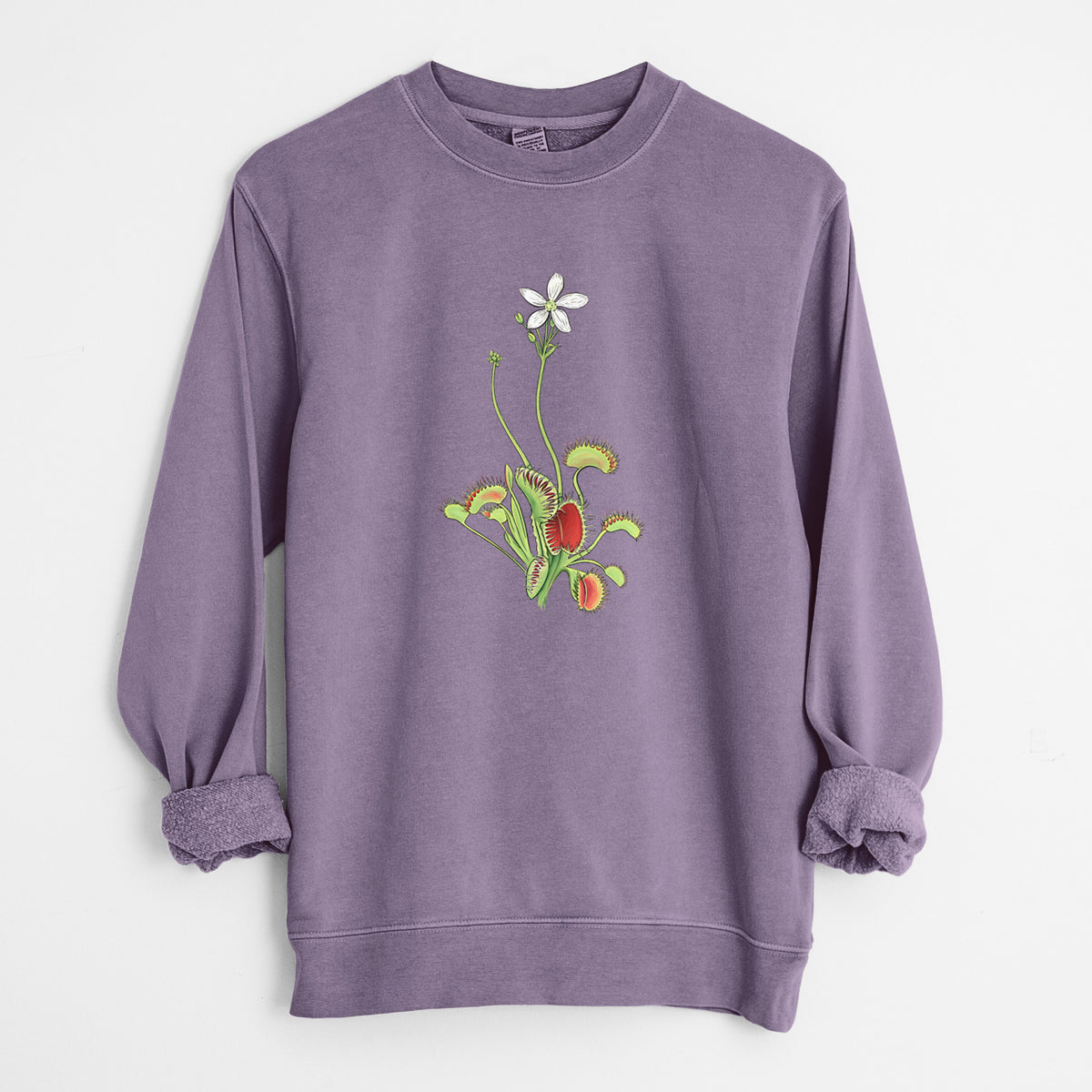 Plum purple pigment dyed crewneck sweatshirt laid flat with the sleeves rolled, printed with a full-color illustration of a Venus flytrap plant with red traps and a small white flower.