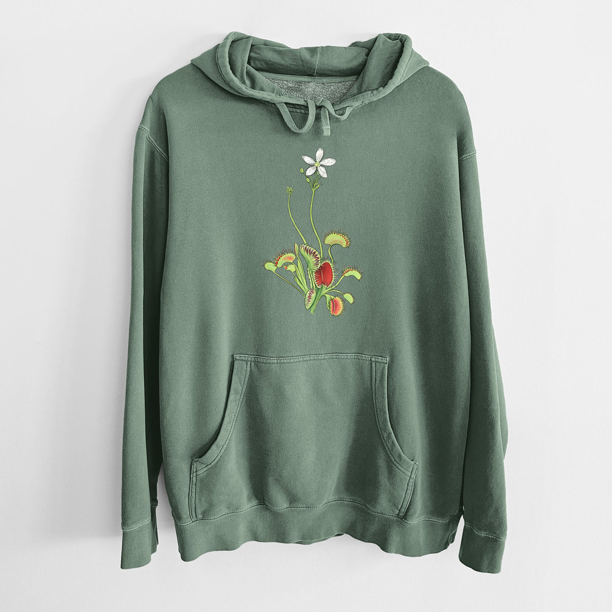 Alpine green pigment dyed hoodie laid flat, printed with a full-color illustration of a Venus flytrap plant with red traps and a small white flower.