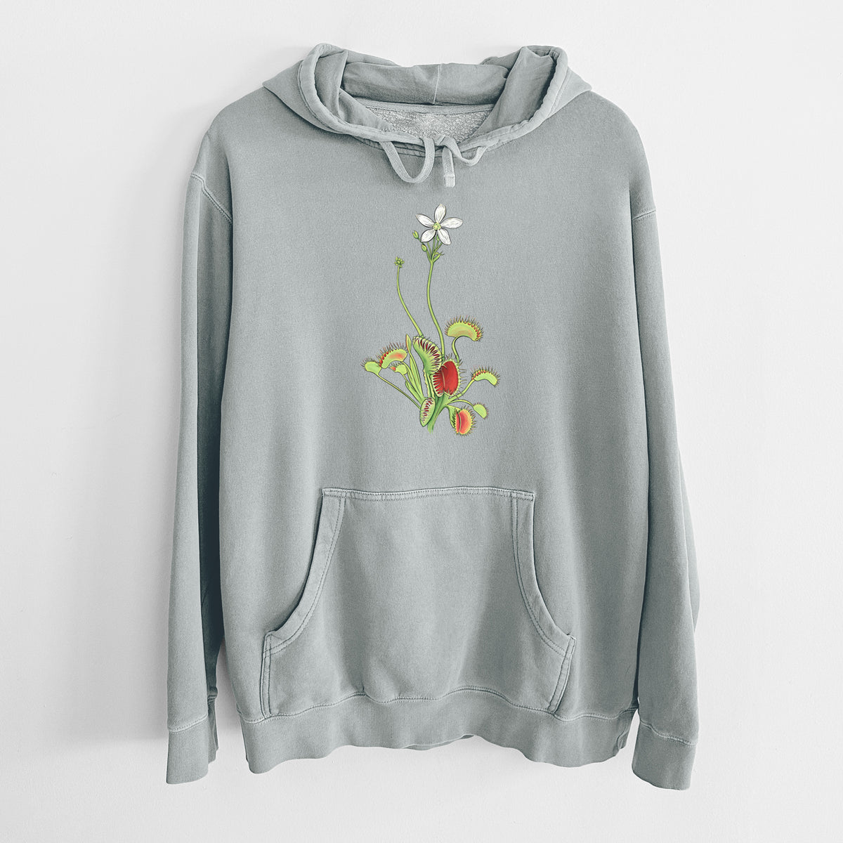 Sage green pigment dyed hoodie laid flat, printed with a full-color illustration of a Venus flytrap plant with red traps and a small white flower.