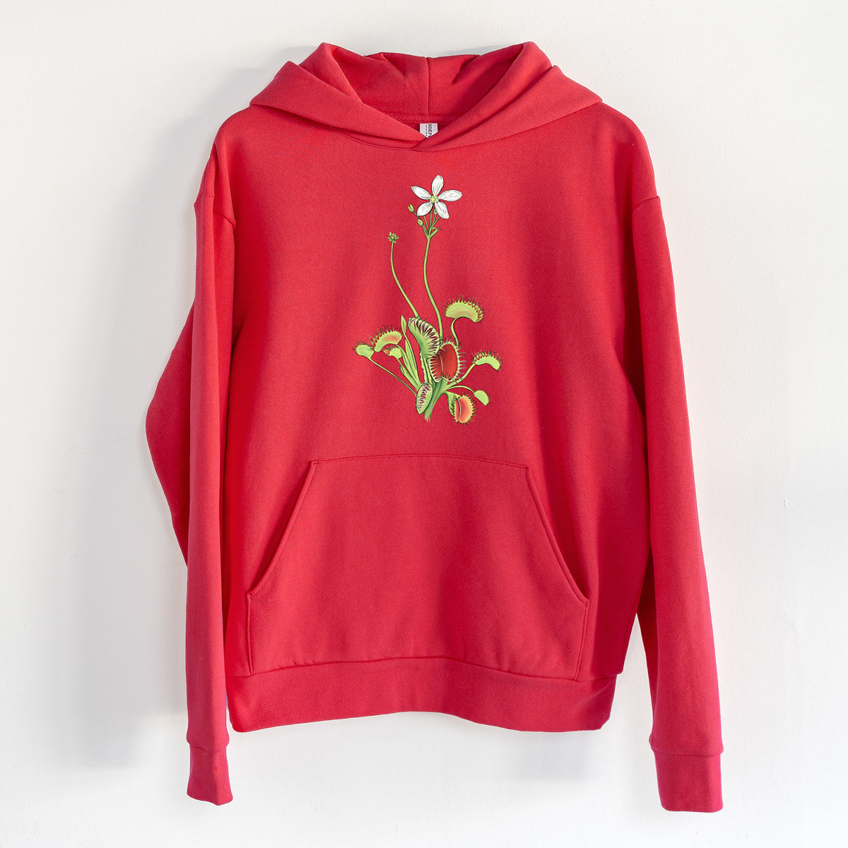 Colorful Carnivorous Venus Fly Trap - Statement Midweight Hoodie in Cherry Red, hanging on a white wall, with a front kangaroo pocket and no drawcords.