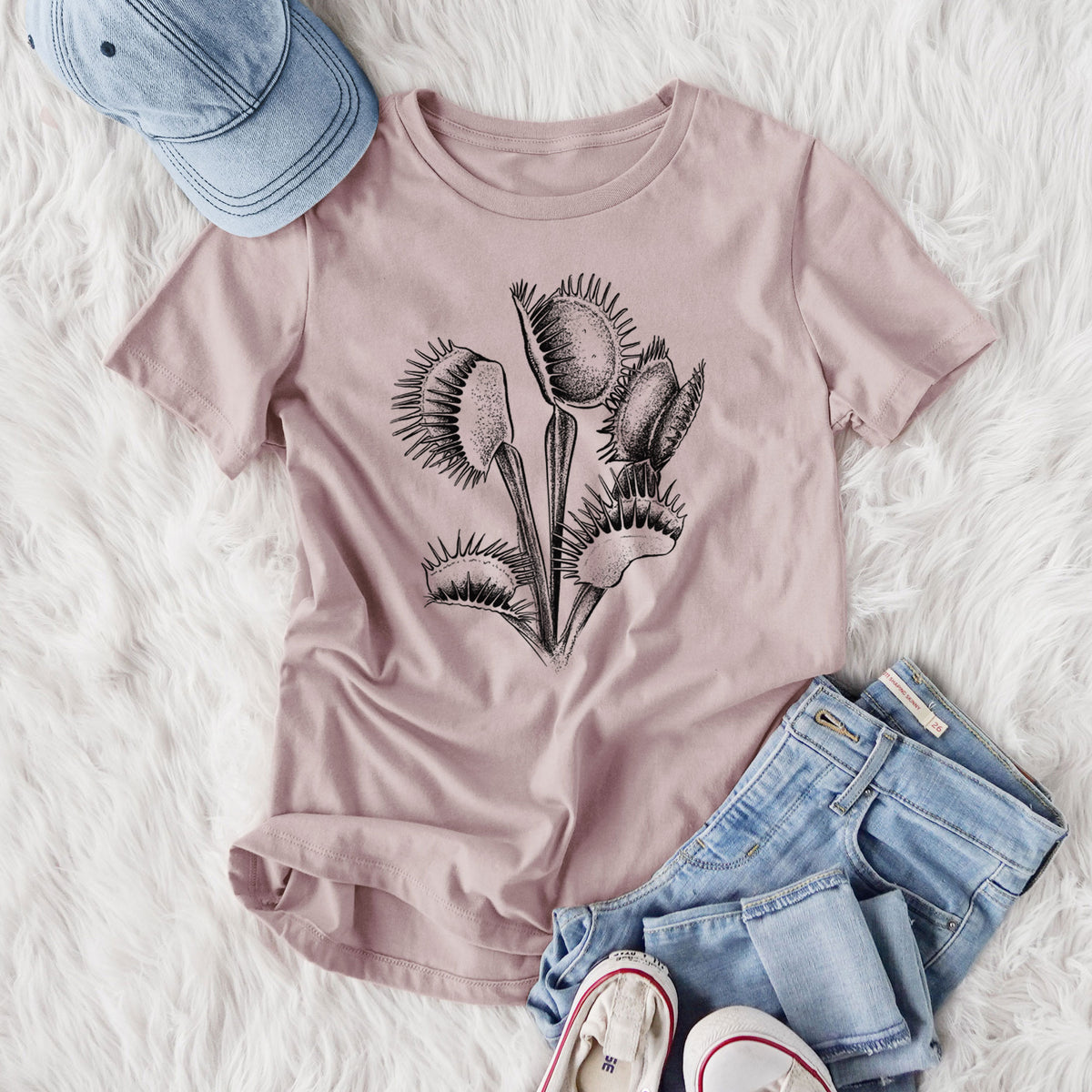 Women's relaxed fit cotton t-shirt printed with a black ink illustration of a Venus flytrap plant with open traps, styled flat on a white faux fur rug with jeans.