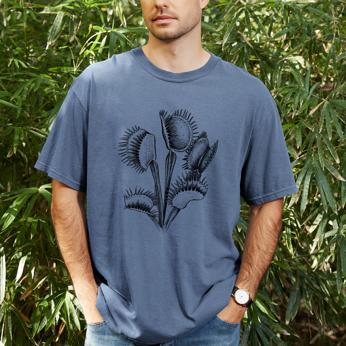 Man wearing a Comfort Colors t-shirt printed with a black ink illustration of a Venus flytrap plant with open traps, outdoors.