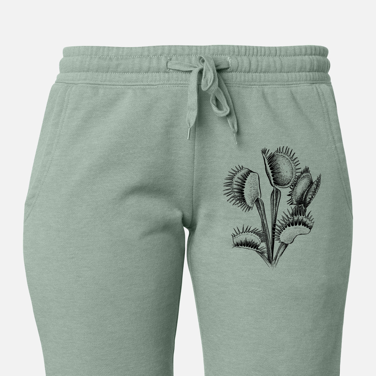 Front of sage green Cali Wave sweatpants, printed with a black ink illustration of a Venus flytrap plant with open traps on the leg.