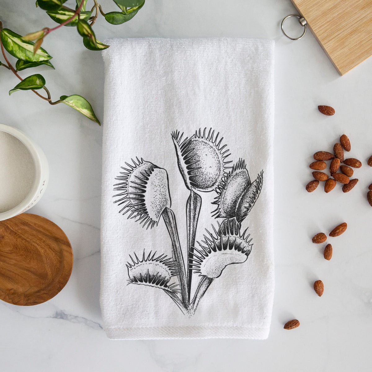 White hand towel printed with a black ink illustration of a Venus flytrap plant with open traps.