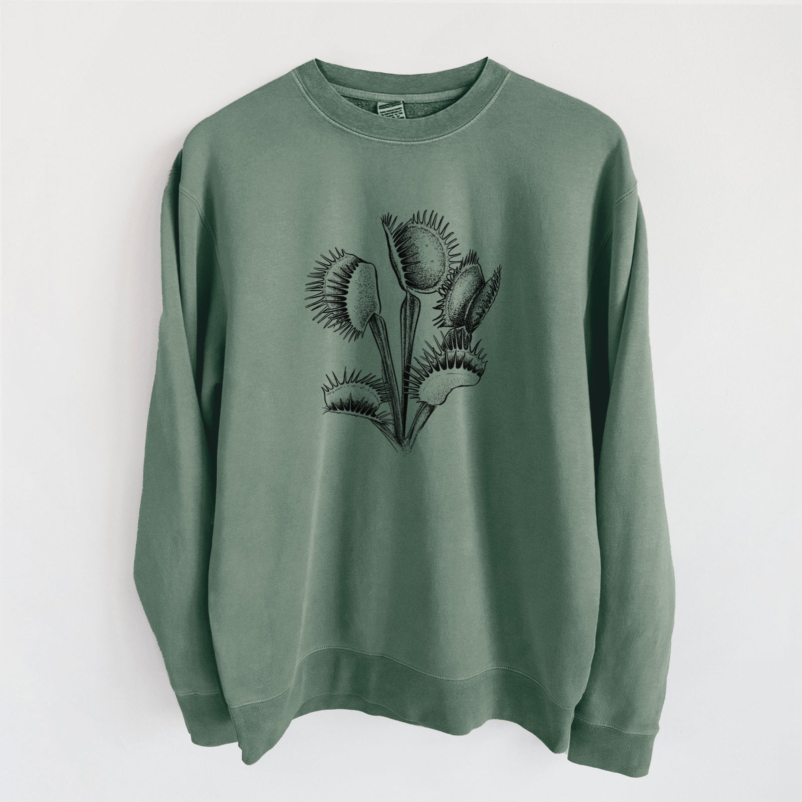 Alpine green pigment dyed crewneck sweatshirt laid flat, printed with a black ink illustration of a Venus flytrap plant with open traps.