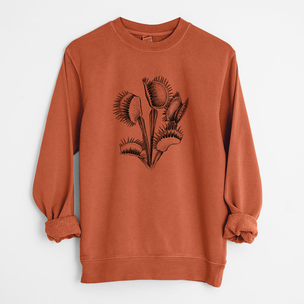 Amber orange pigment dyed crewneck sweatshirt laid flat with the sleeves rolled, printed with a black ink illustration of a Venus flytrap plant with open traps.
