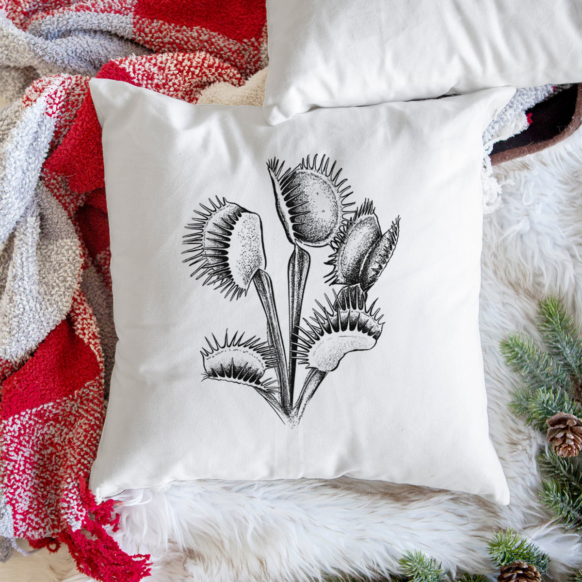 White pillow cover printed with a black ink illustration of a Venus flytrap plant with open traps, on a woven chair.