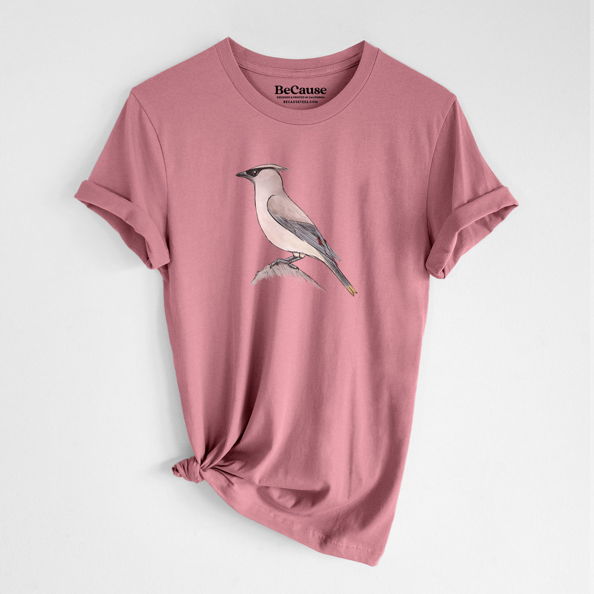 Mauve pink lightweight cotton t-shirt laid flat with the sleeves rolled, printed with a full-color illustration of a cedar waxwing perched on a branch.