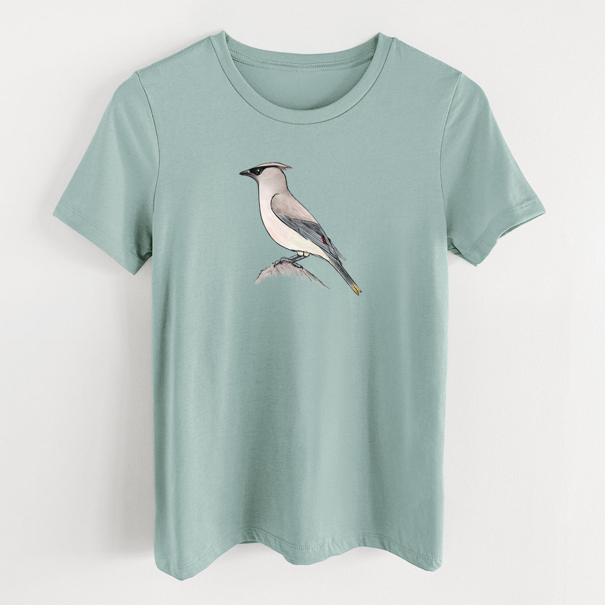 Dusty blue women's relaxed fit cotton t-shirt laid flat, printed with a full-color illustration of a cedar waxwing perched on a branch.