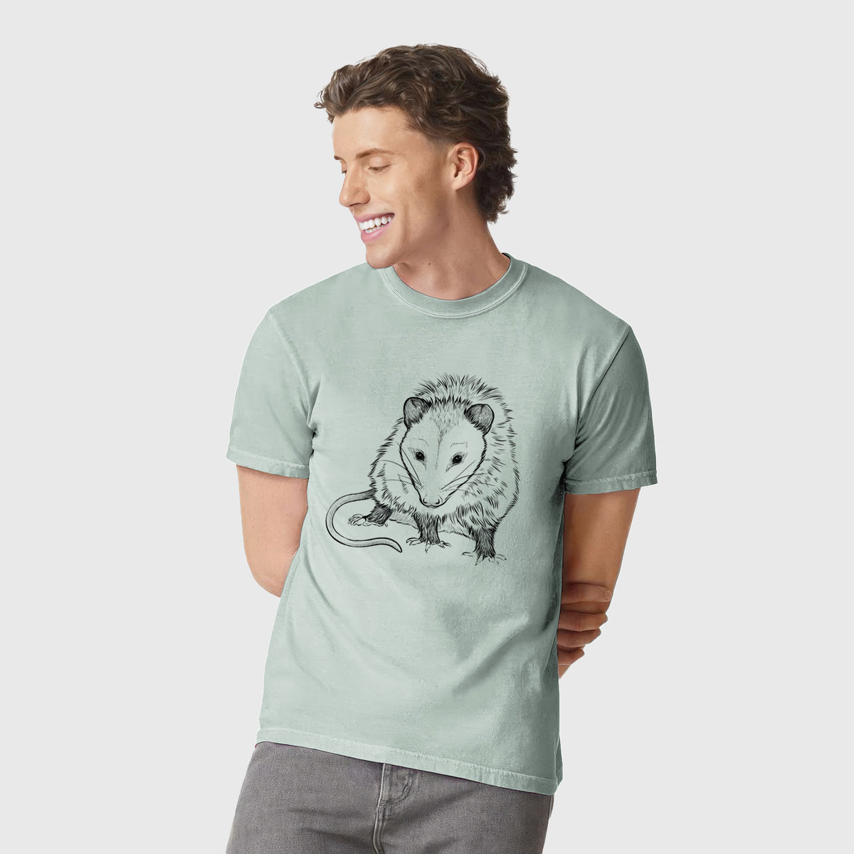 Man wearing a Comfort Colors t-shirt printed with a detailed black ink illustration of a Virginia opossum standing with its long tail curled.