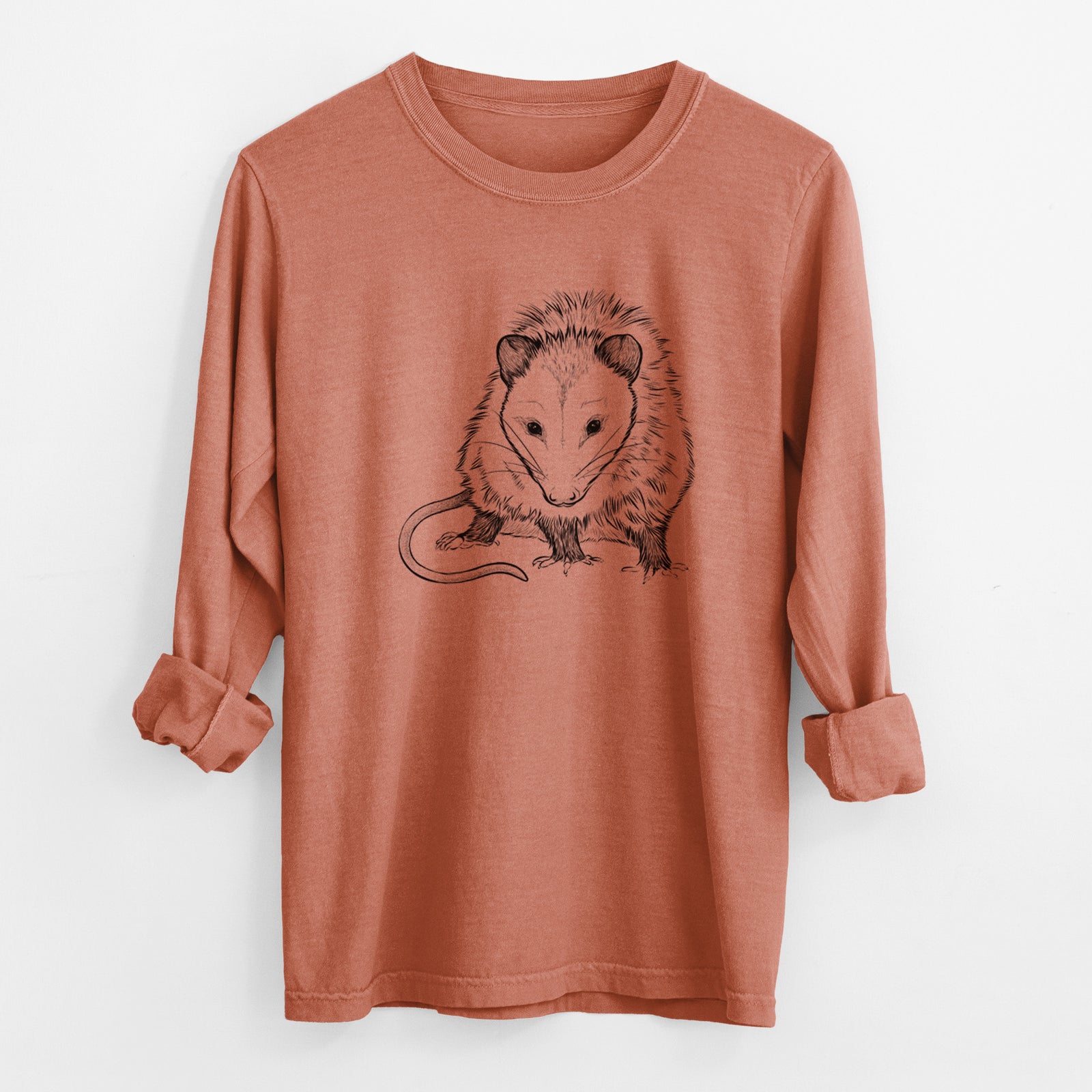 Yam burnt orange Comfort Colors long sleeve shirt laid flat with the cuffs rolled, printed with a detailed black ink illustration of a Virginia opossum standing with its long tail curled.