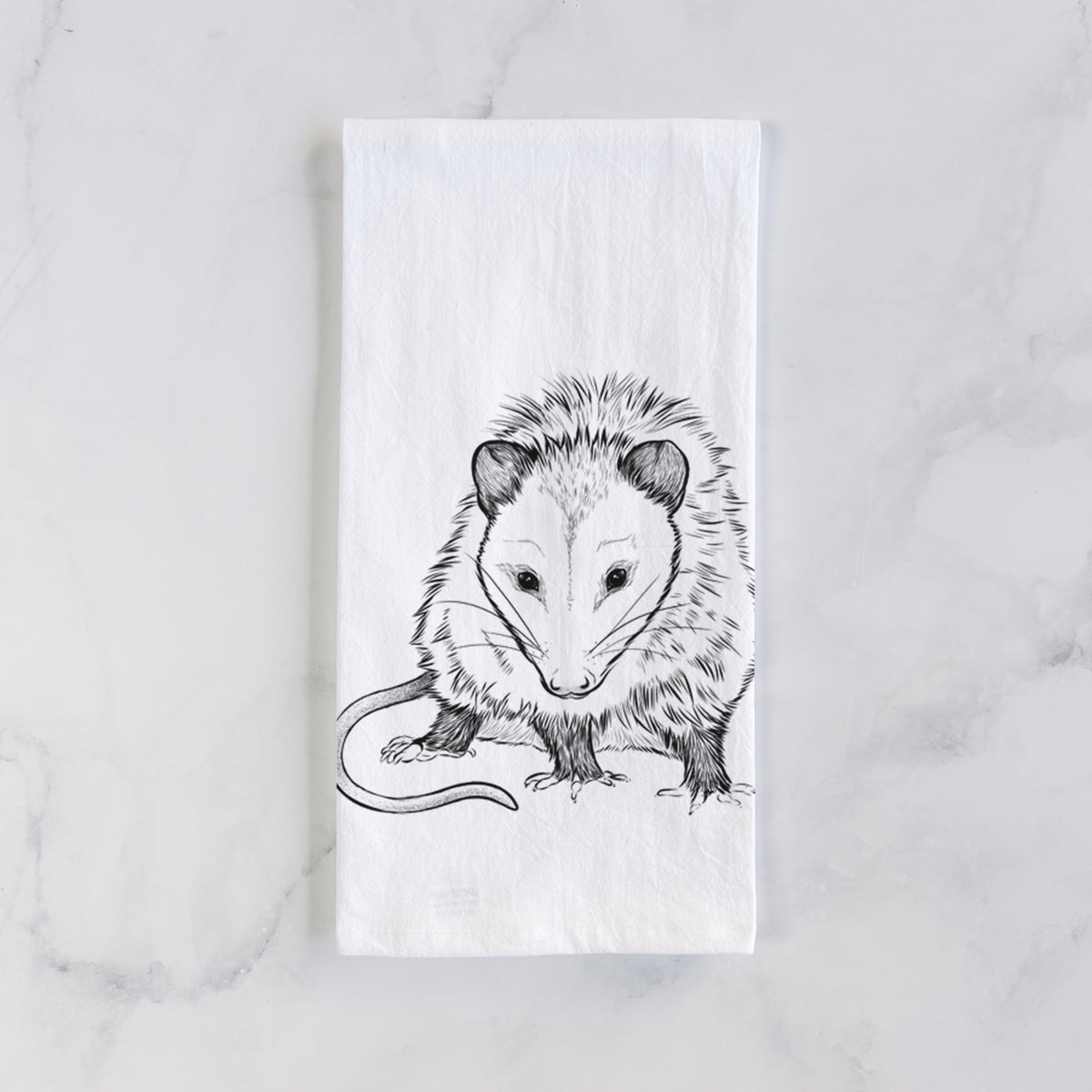 White cotton tea towel laid flat on marble, printed with a detailed black ink illustration of a Virginia opossum standing with its long tail curled.