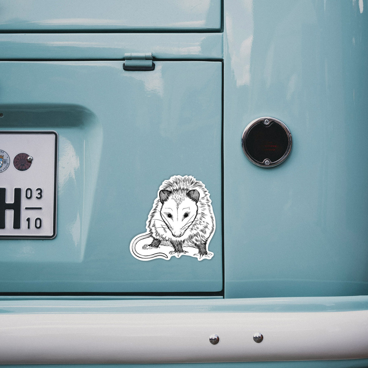 4 inch vinyl decal of a detailed black ink illustration of a Virginia opossum standing with its long tail curled on the back of a van.
