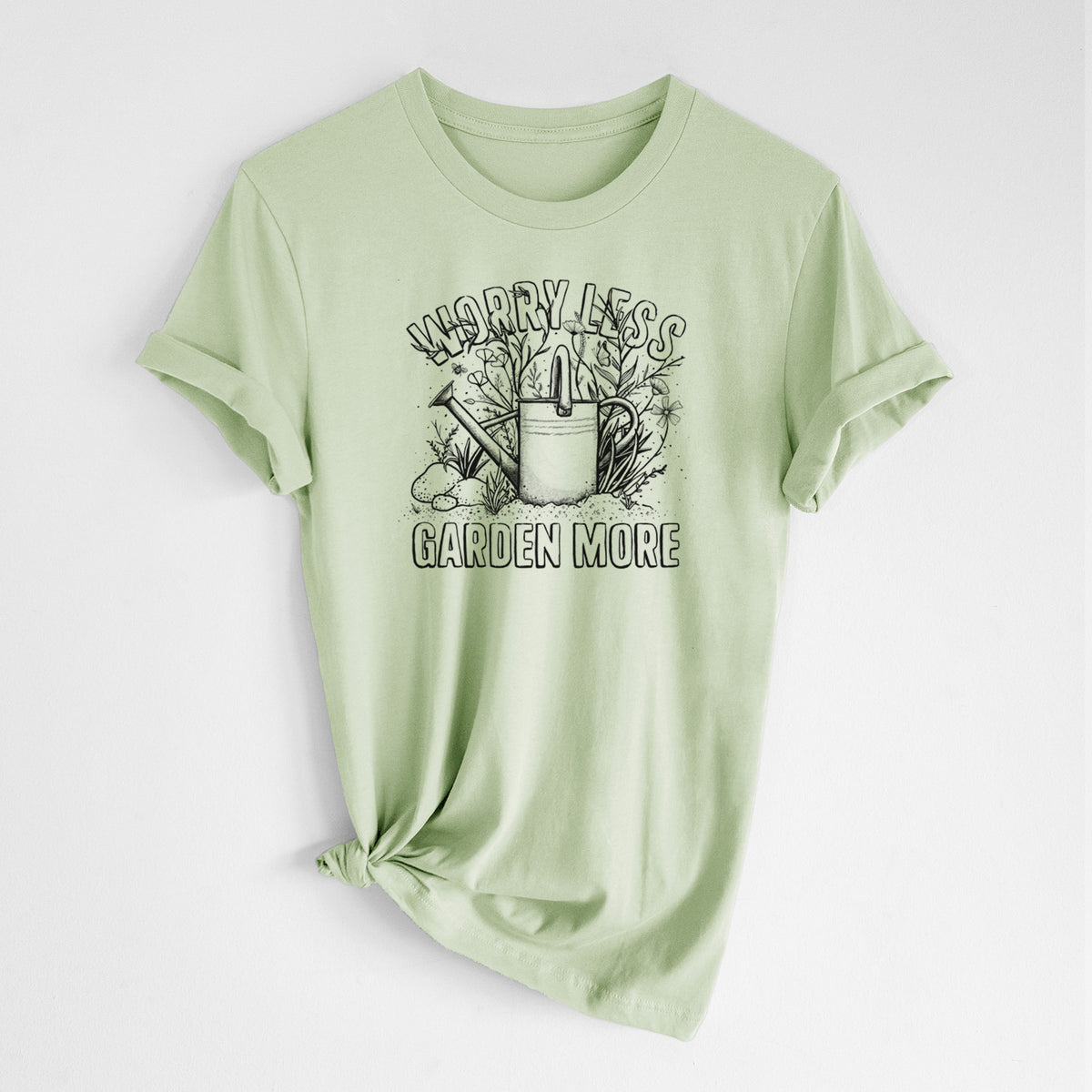 Spring green lightweight cotton t-shirt laid flat with the sleeves rolled, printed with a black ink watering can surrounded by flowers and garden tools, with the words Worry Less, Garden More.
