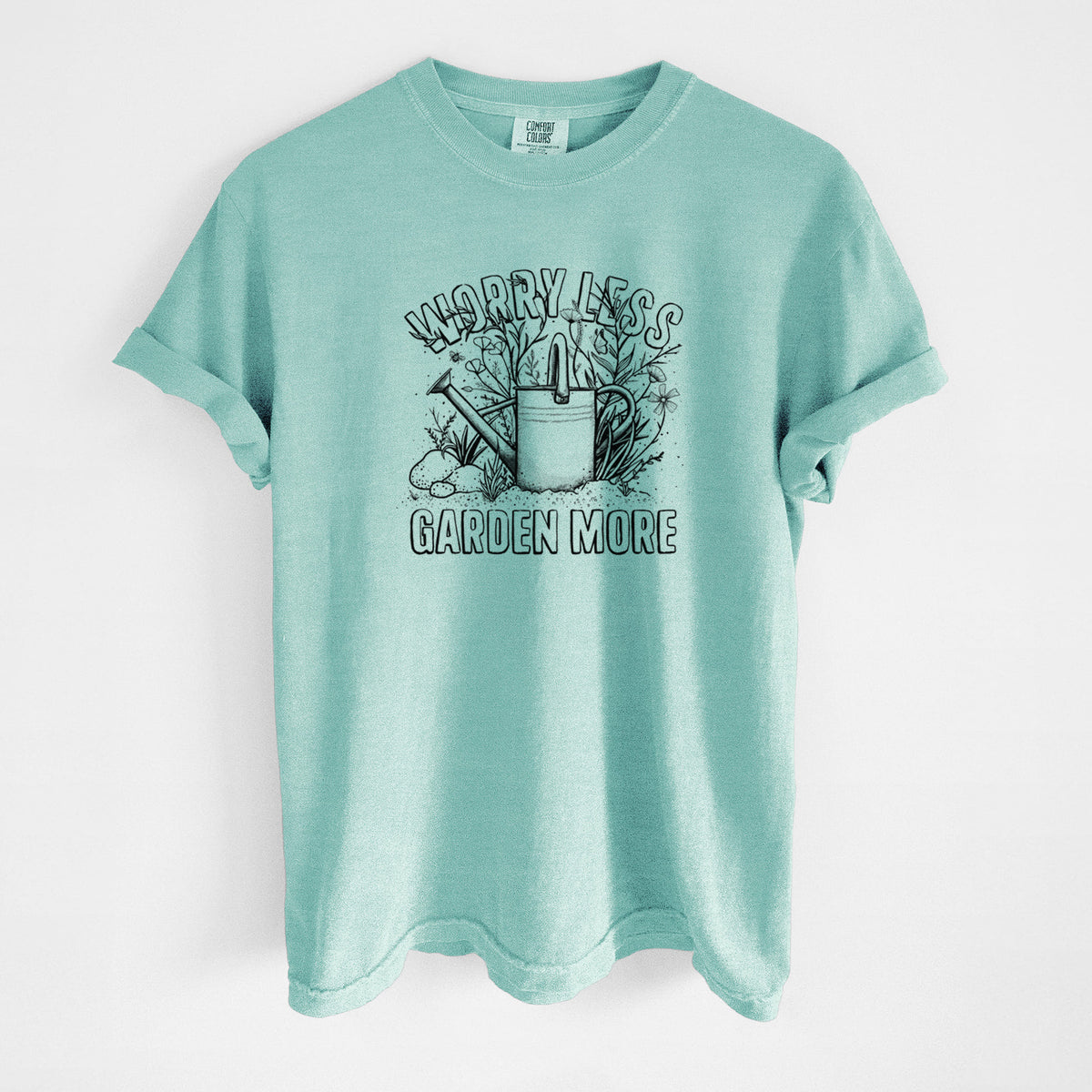 Chalky mint Comfort Colors t-shirt laid flat, printed with a black ink watering can surrounded by flowers and garden tools, with the words Worry Less, Garden More.