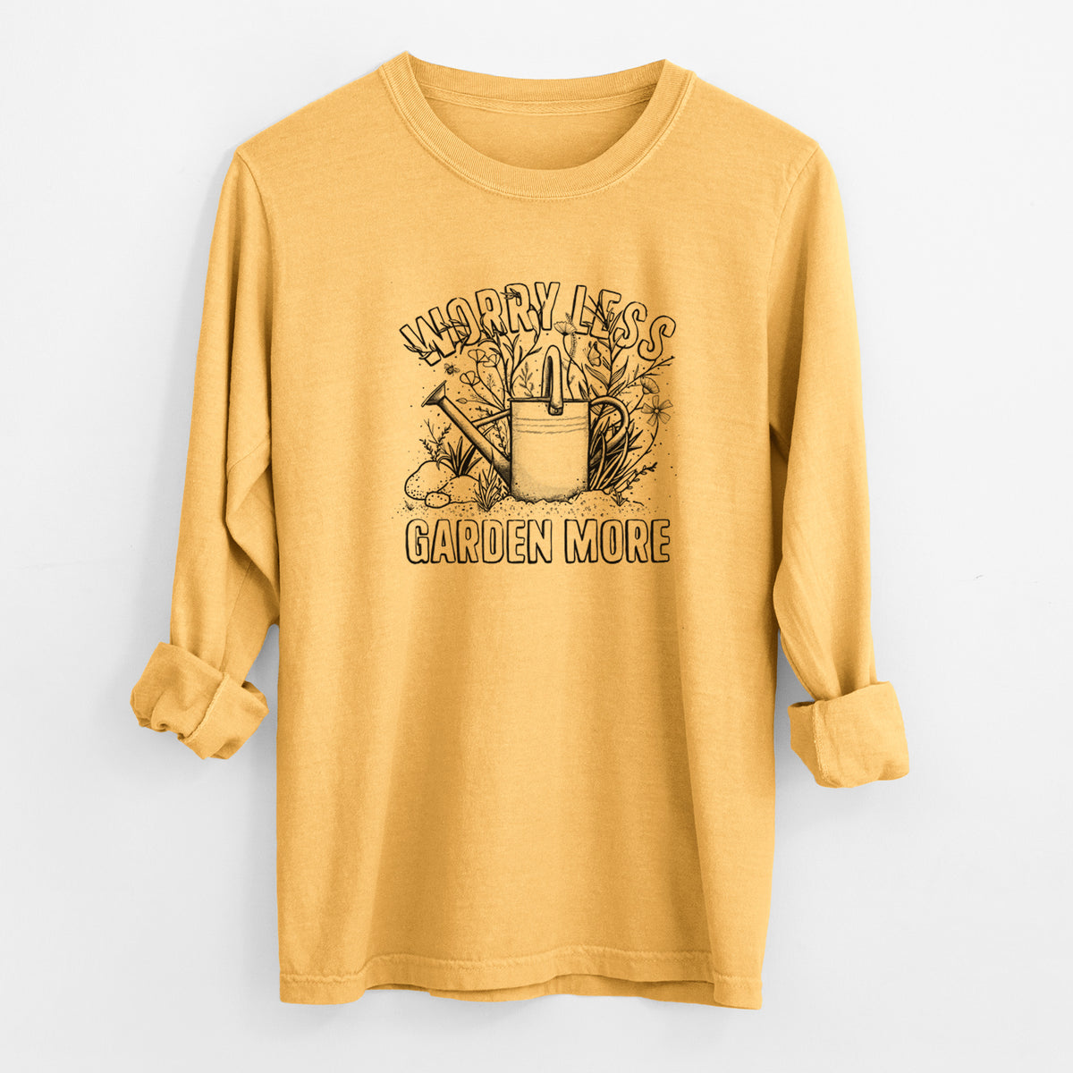 Golden wheat yellow Comfort Colors long sleeve shirt laid flat with the cuffs rolled, printed with a black ink watering can surrounded by flowers and garden tools, with the words Worry Less, Garden More.