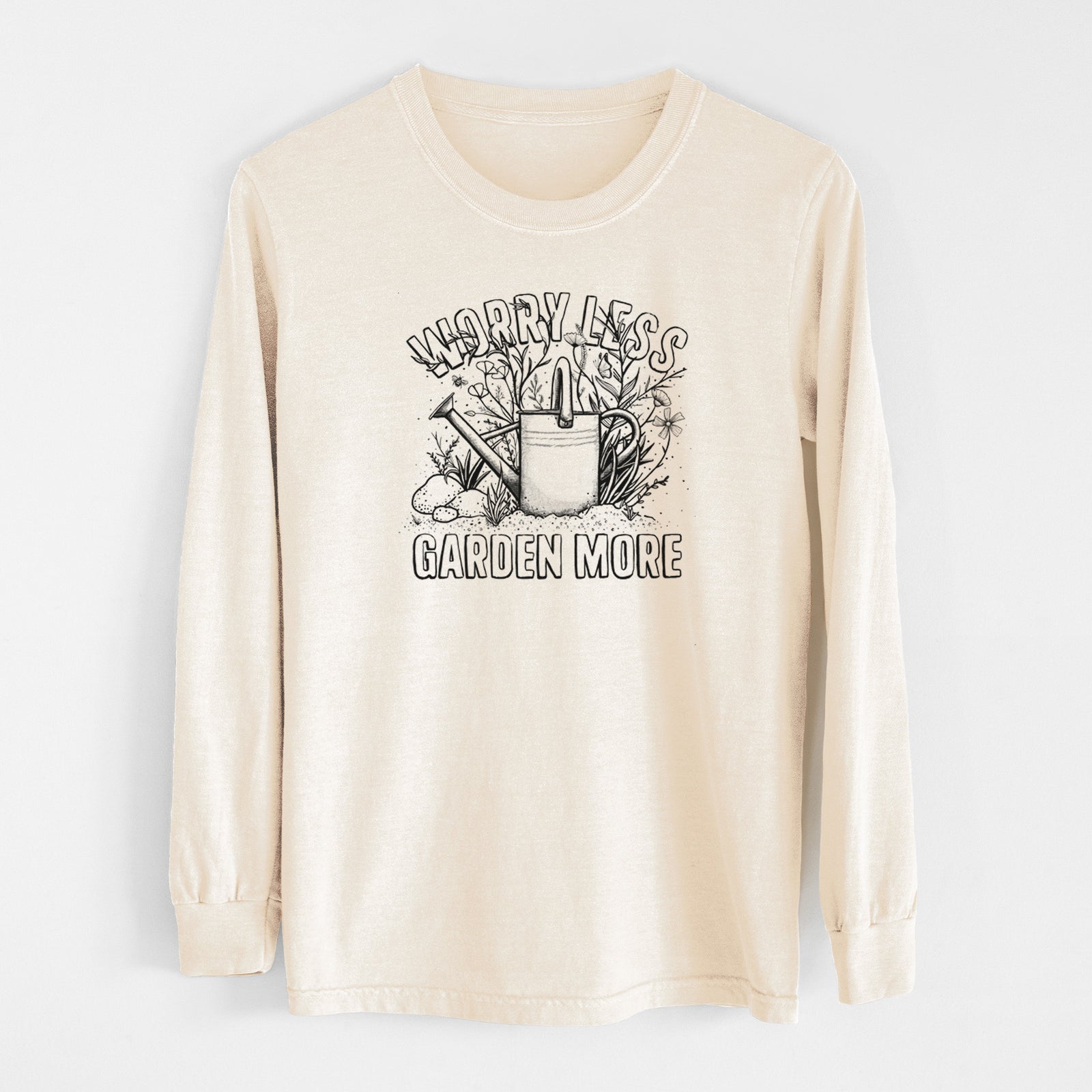 Ivory Comfort Colors long sleeve shirt laid flat, printed with a black ink watering can surrounded by flowers and garden tools, with the words Worry Less, Garden More.