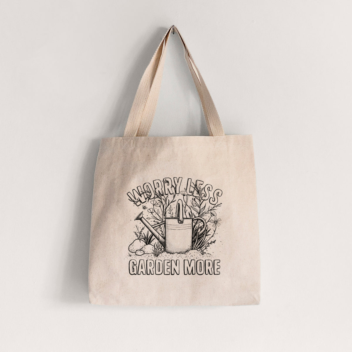 Natural canvas tote bag printed with a black ink watering can surrounded by flowers and garden tools, with the words Worry Less, Garden More.