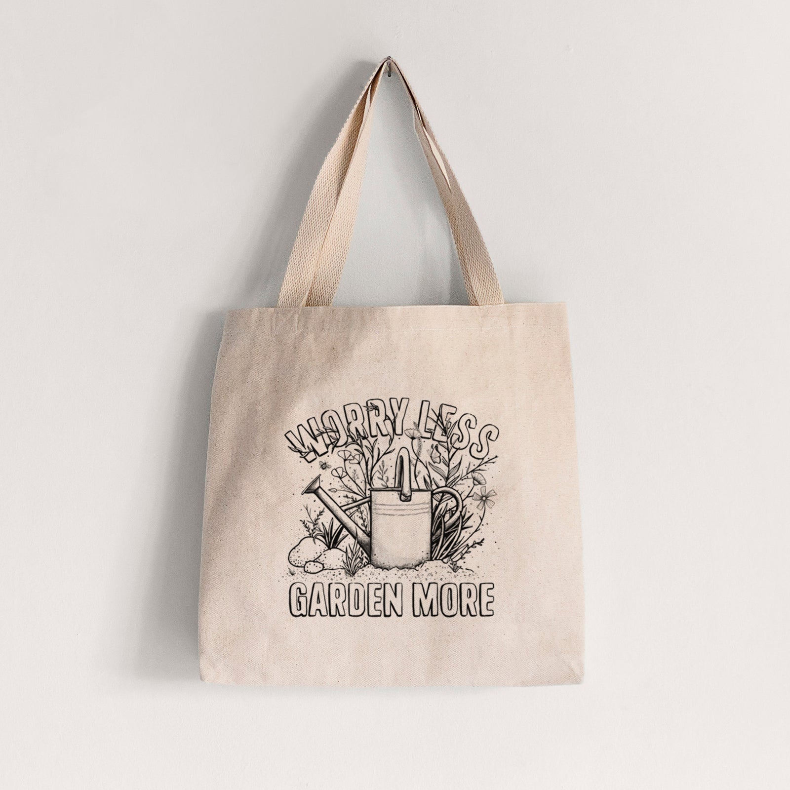 Natural canvas tote bag printed with a black ink watering can surrounded by flowers and garden tools, with the words Worry Less, Garden More.