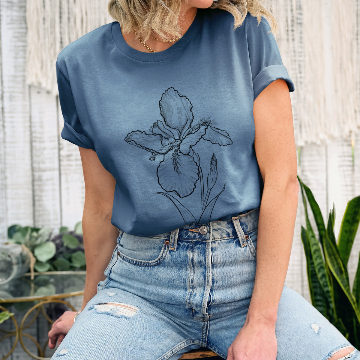 Woman wearing a steel blue lightweight cotton t-shirt printed with a black ink line drawing of a wall iris flower on its stem.