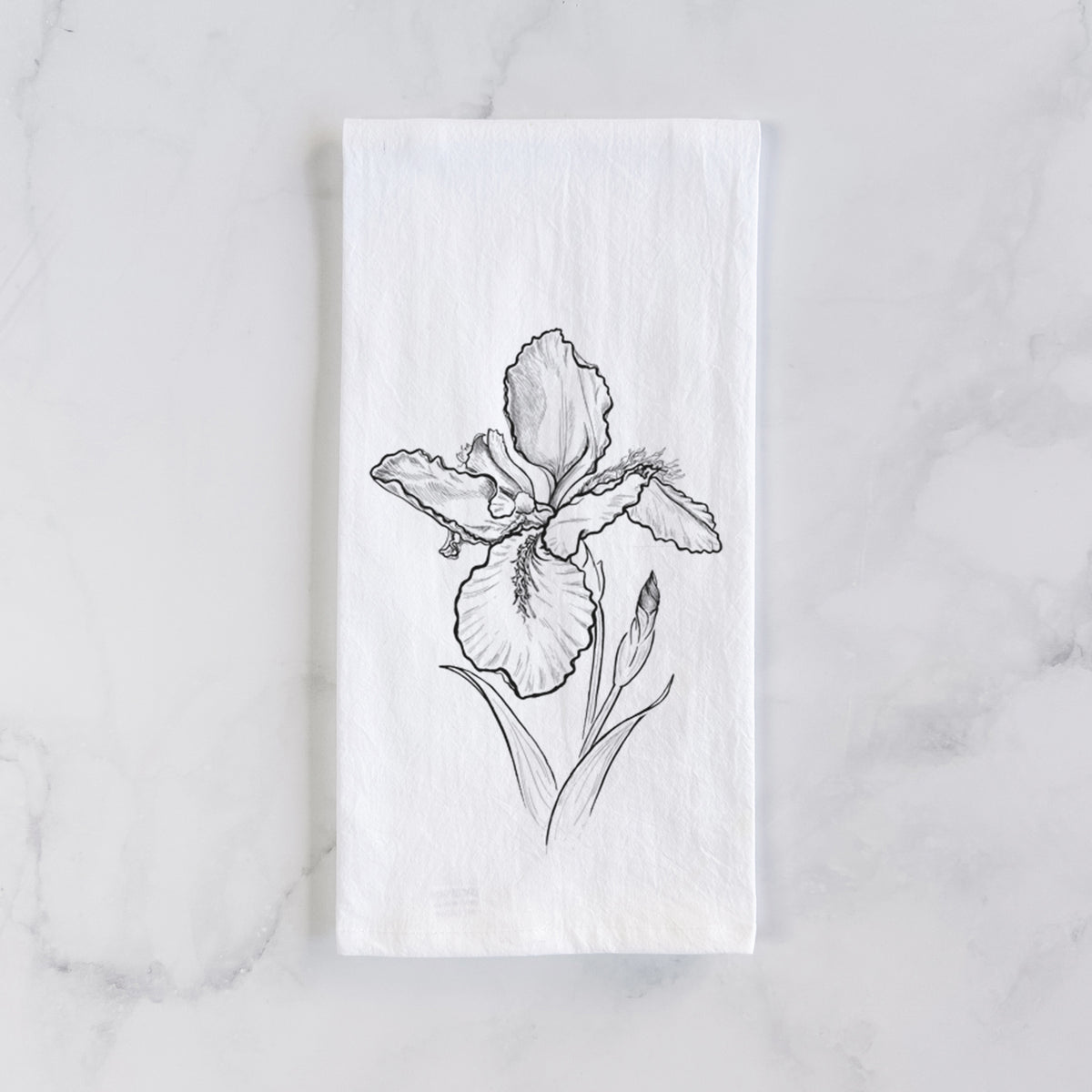 White cotton tea towel laid flat on marble, printed with a black ink line drawing of a wall iris flower on its stem.