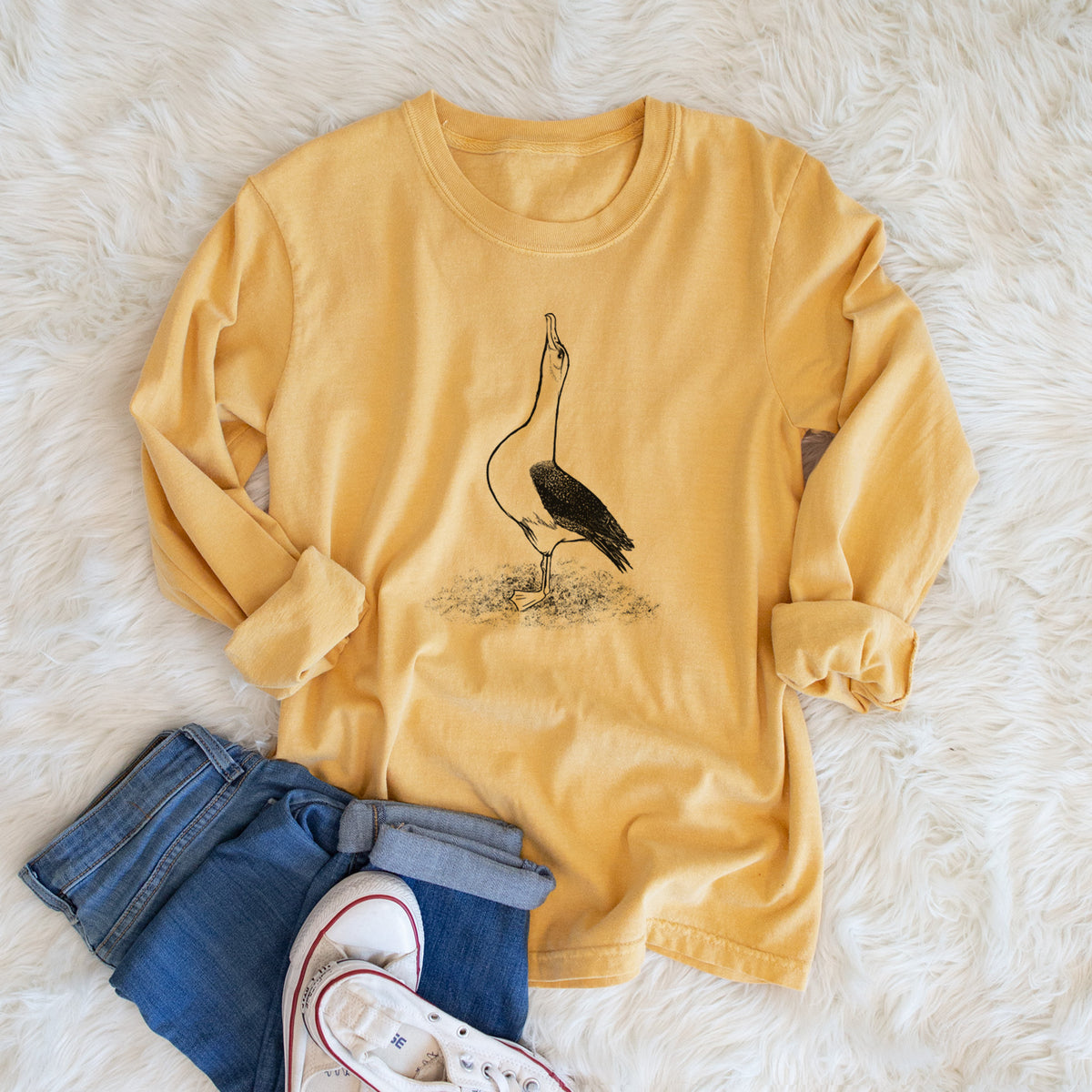 Golden wheat yellow Comfort Colors long sleeve shirt printed with a black ink illustration of a wandering albatross with its head raised, shown in a lifestyle photo.