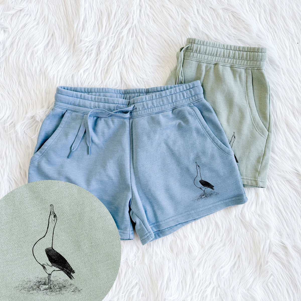 Two pairs of Cali Wave shorts in different colors printed with a black ink illustration of a wandering albatross with its head raised, with a close-up of the print.