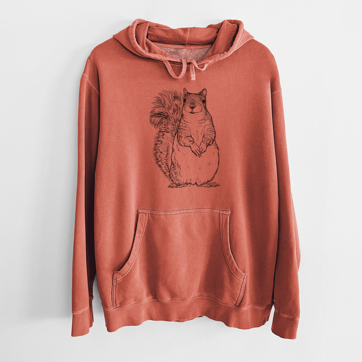 Amber orange pigment dyed hoodie laid flat, printed with a detailed black ink illustration of a western grey squirrel sitting upright with a bushy tail.