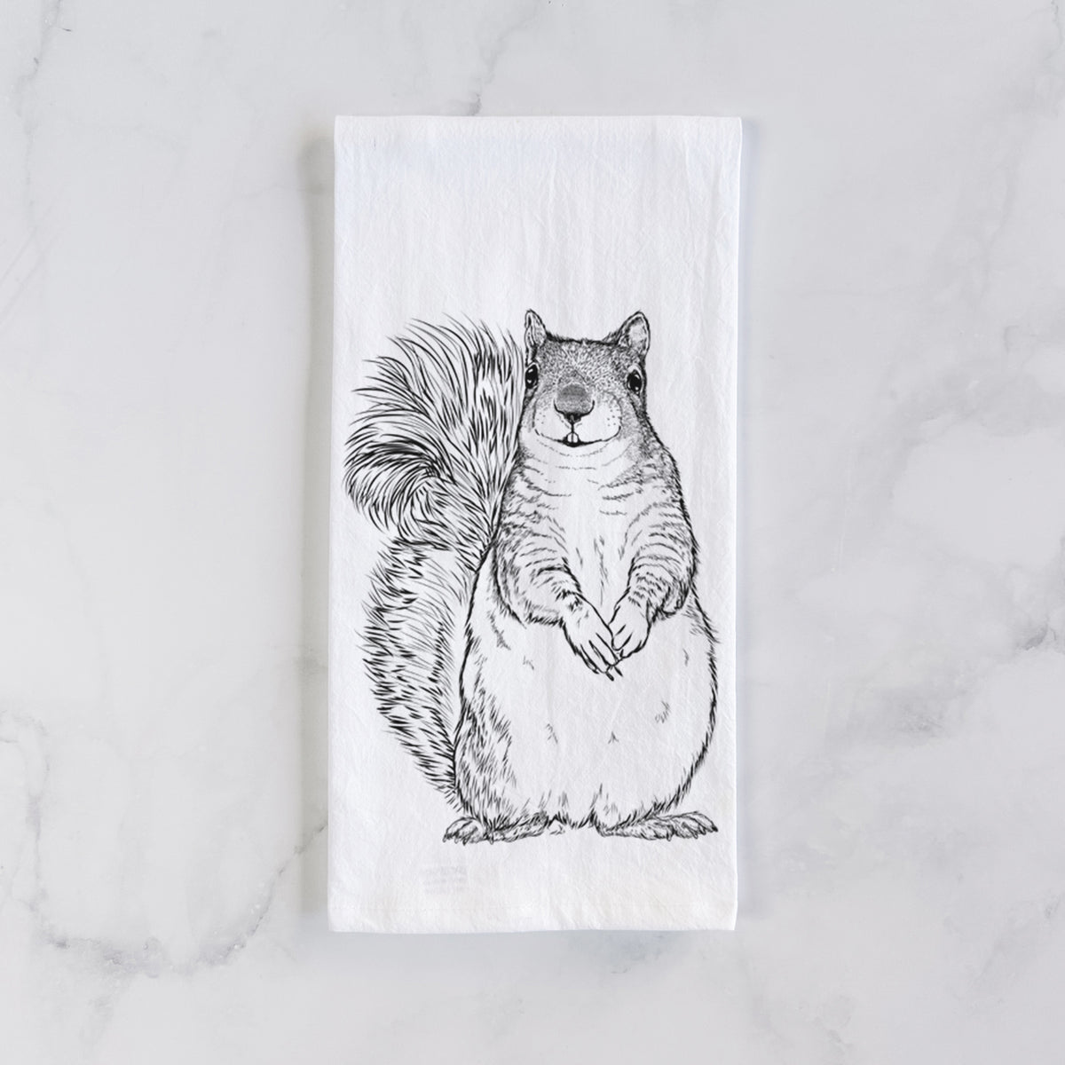 White cotton tea towel laid flat on marble, printed with a detailed black ink illustration of a western grey squirrel sitting upright with a bushy tail.