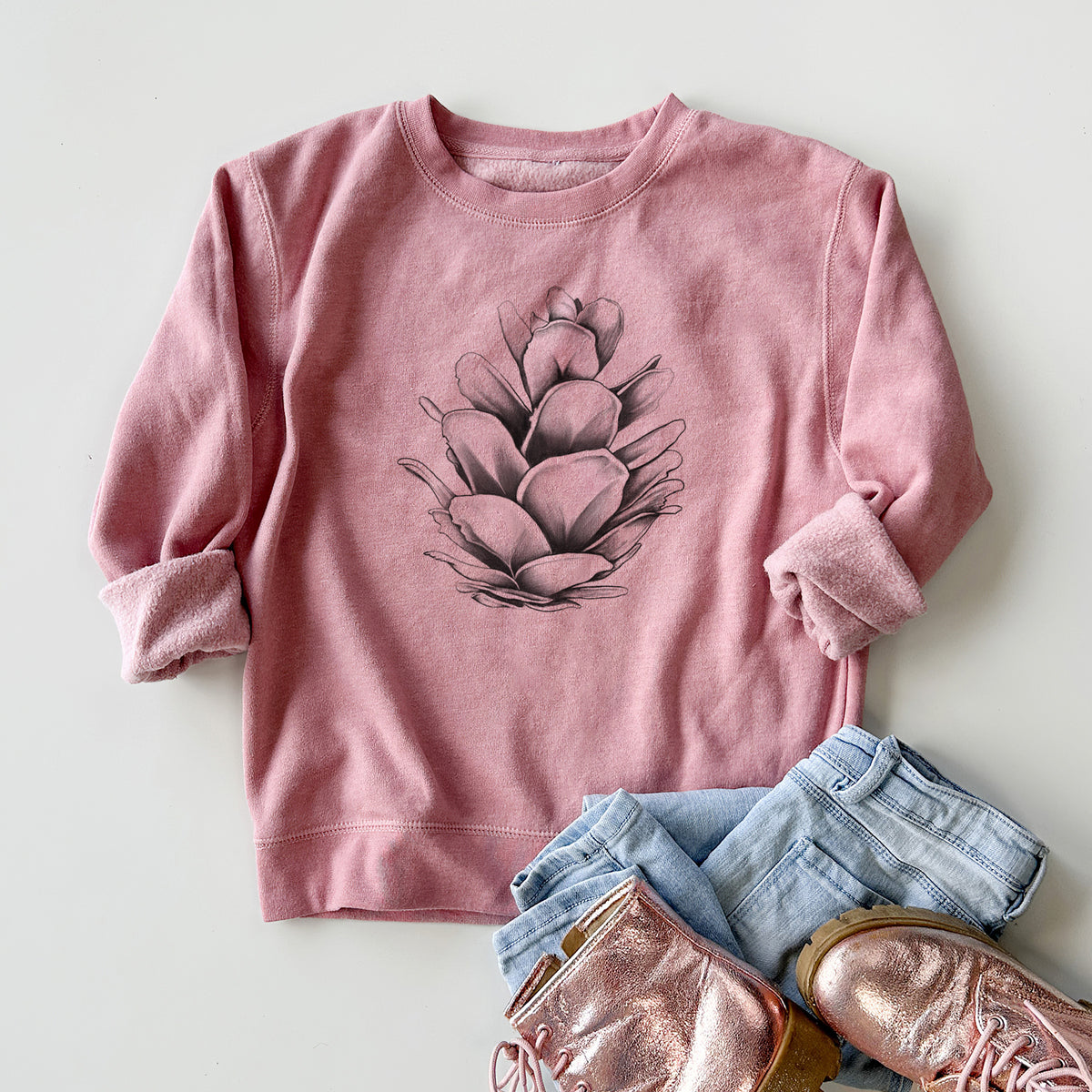 Youth crewneck sweatshirt printed with a detailed black ink illustration of a western hemlock pine cone, styled flat with jeans and boots.
