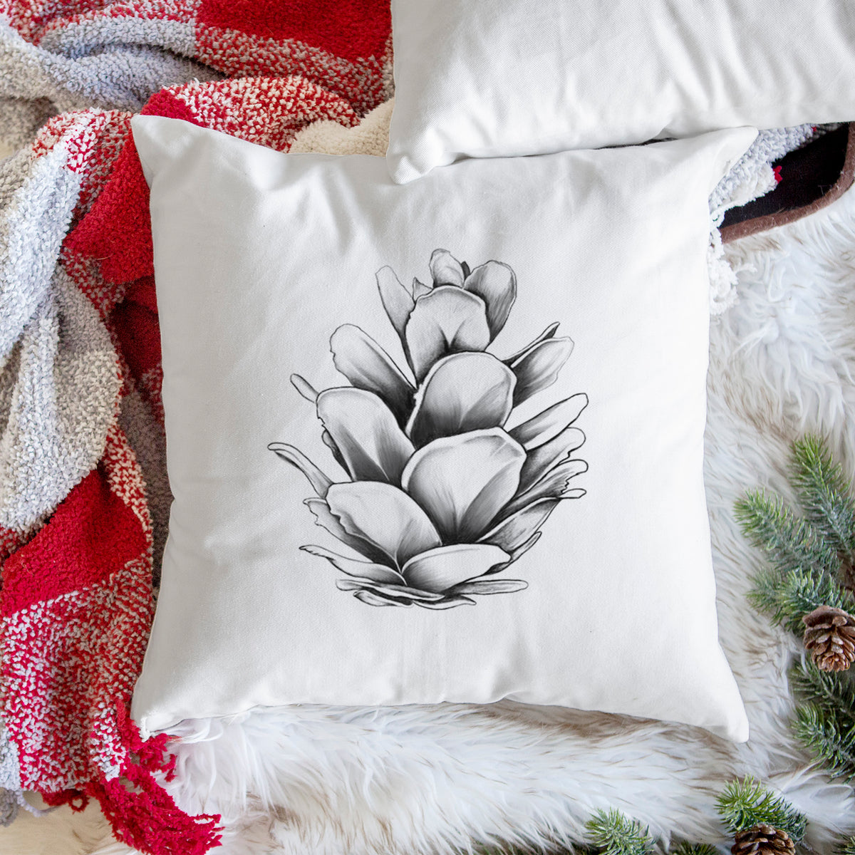 White pillow cover printed with a detailed black ink illustration of a western hemlock pine cone, on a woven chair.