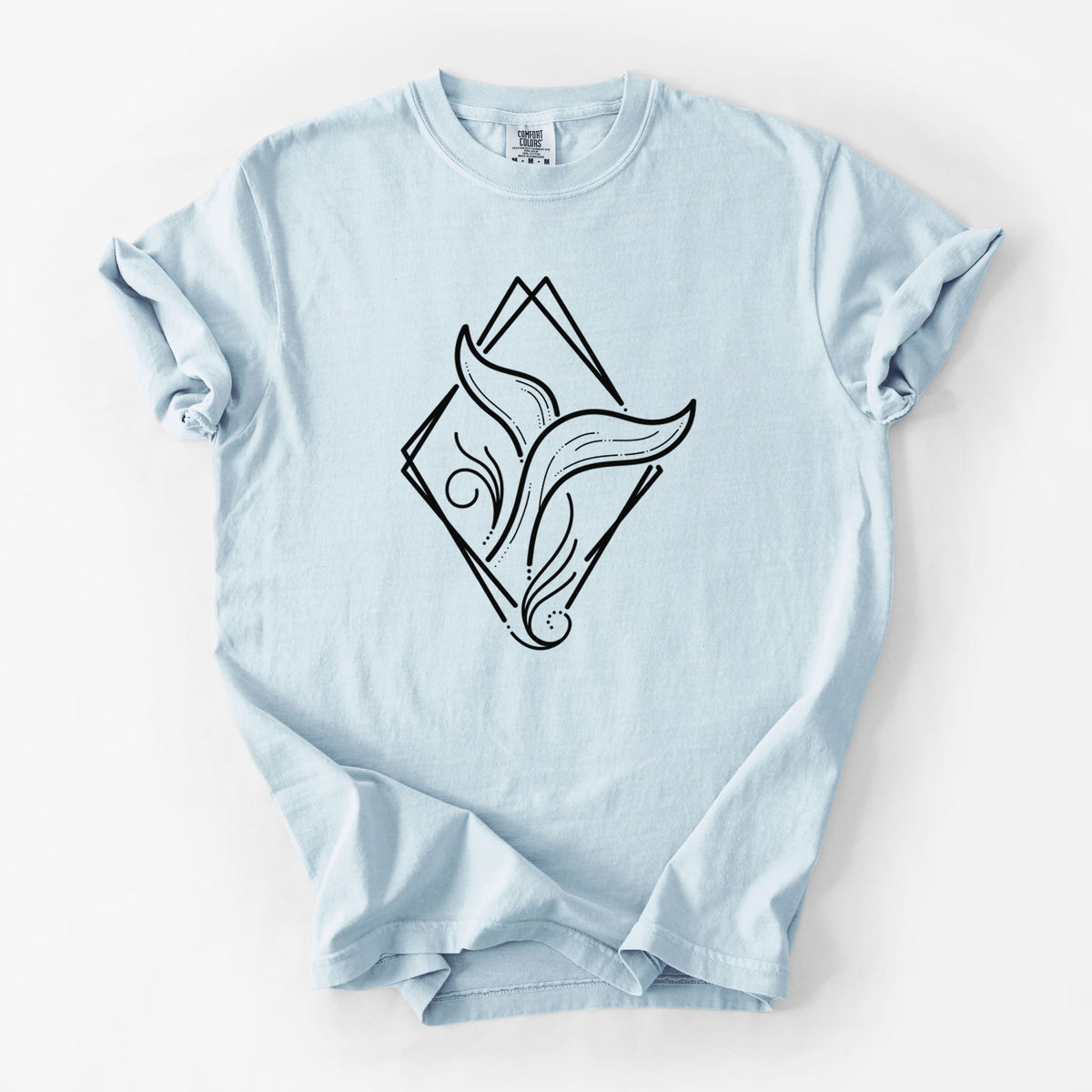 Chambray blue Comfort Colors t-shirt laid flat, printed with a black line art whale tail rising from a wave inside a diamond outline.