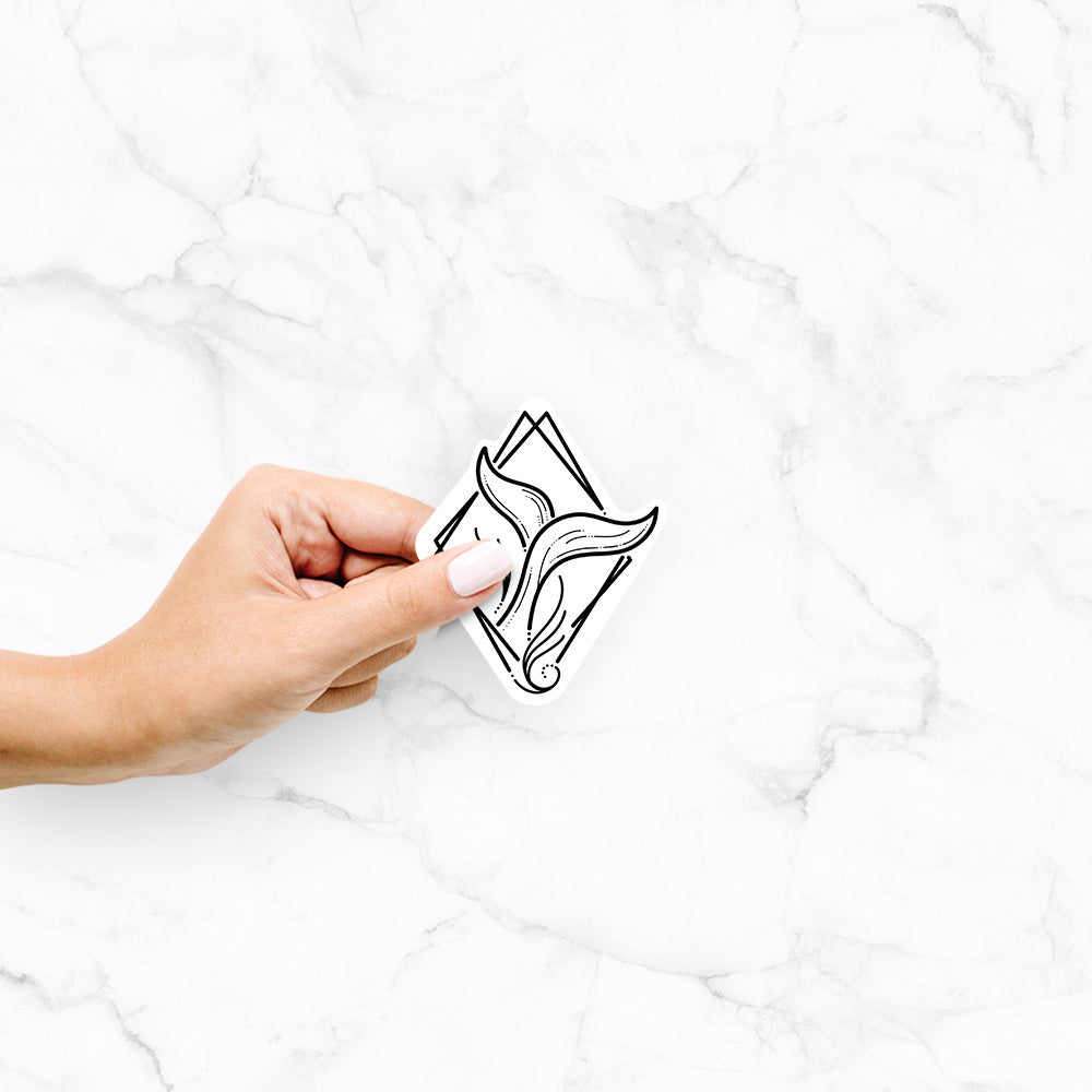 Hand holding a 4 inch vinyl decal of a black line art whale tail rising from a wave inside a diamond outline.