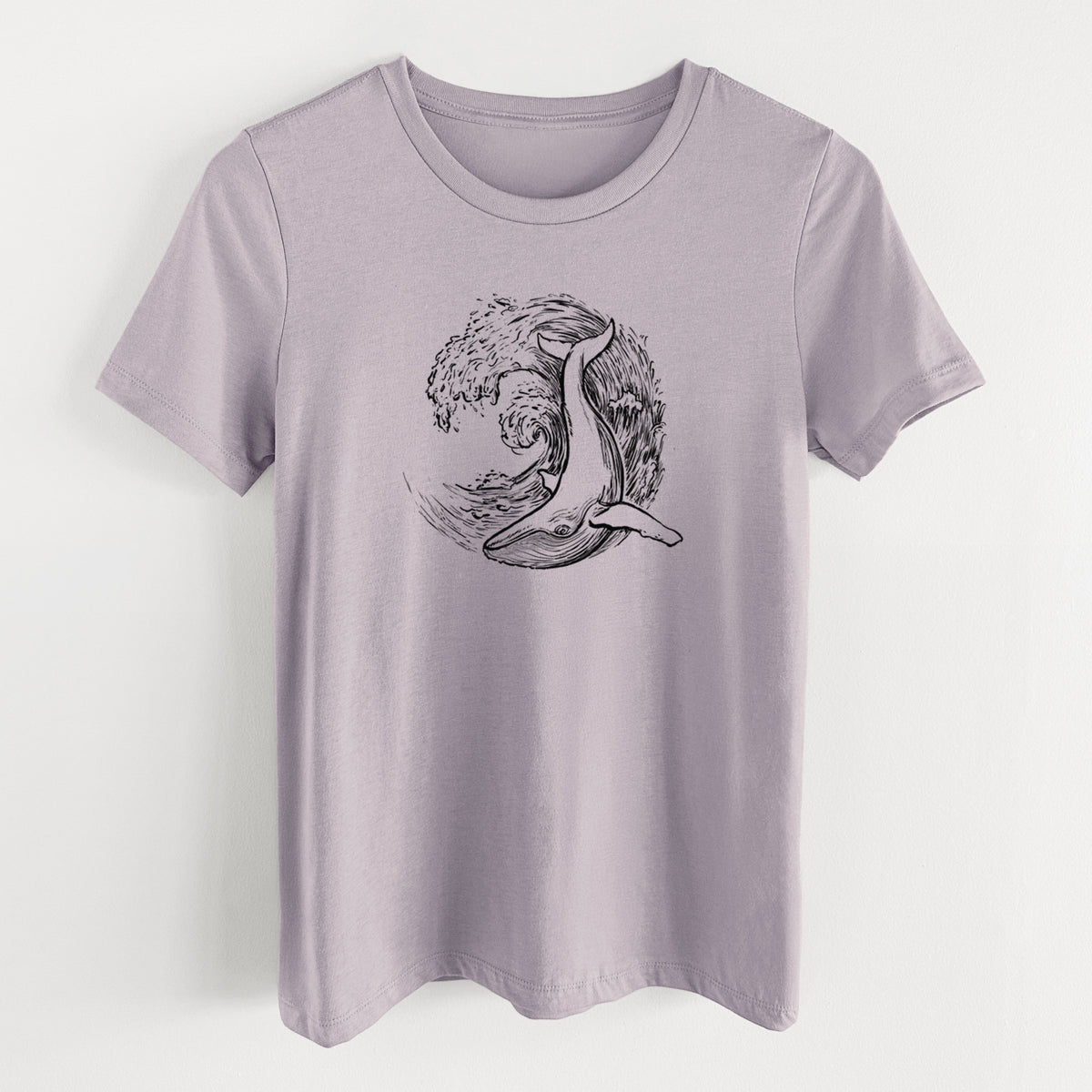Light violet women's relaxed fit cotton t-shirt laid flat, printed with a black ink illustration of a humpback whale swimming inside a curling ocean wave.