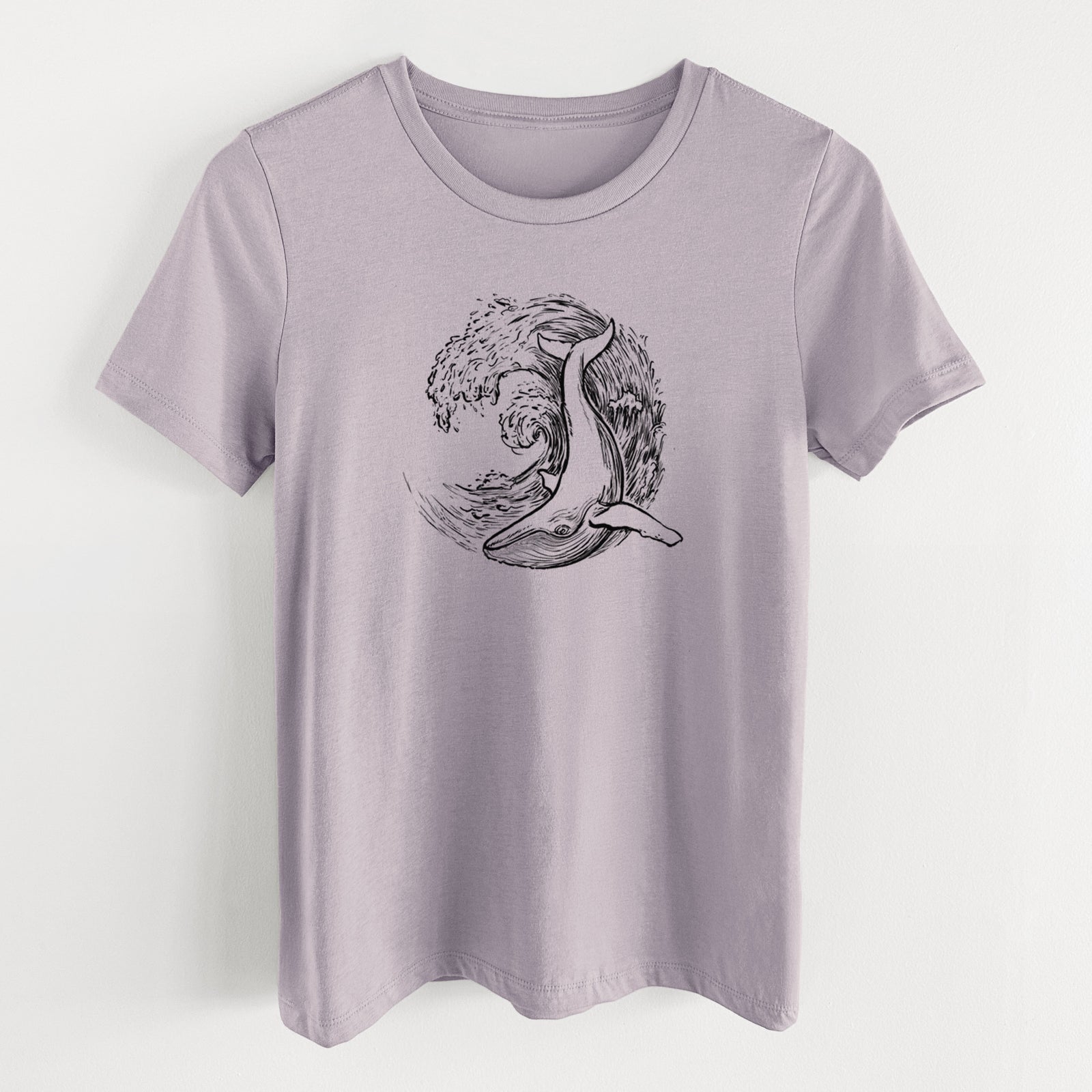 Light violet women's relaxed fit cotton t-shirt laid flat, printed with a black ink illustration of a humpback whale swimming inside a curling ocean wave.