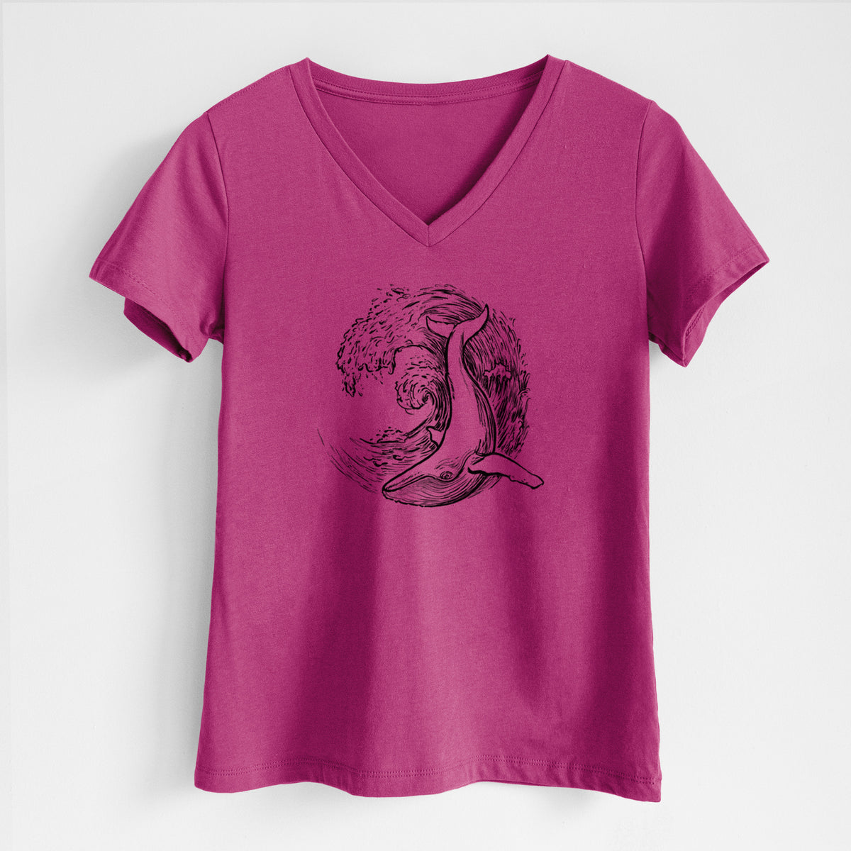 Berry pink women's relaxed fit cotton V-neck t-shirt laid flat, printed with a black ink illustration of a humpback whale swimming inside a curling ocean wave.