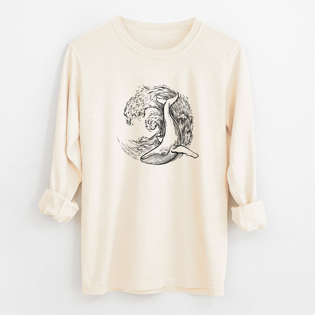 Ivory Comfort Colors long sleeve shirt laid flat with the cuffs rolled, printed with a black ink illustration of a humpback whale swimming inside a curling ocean wave.