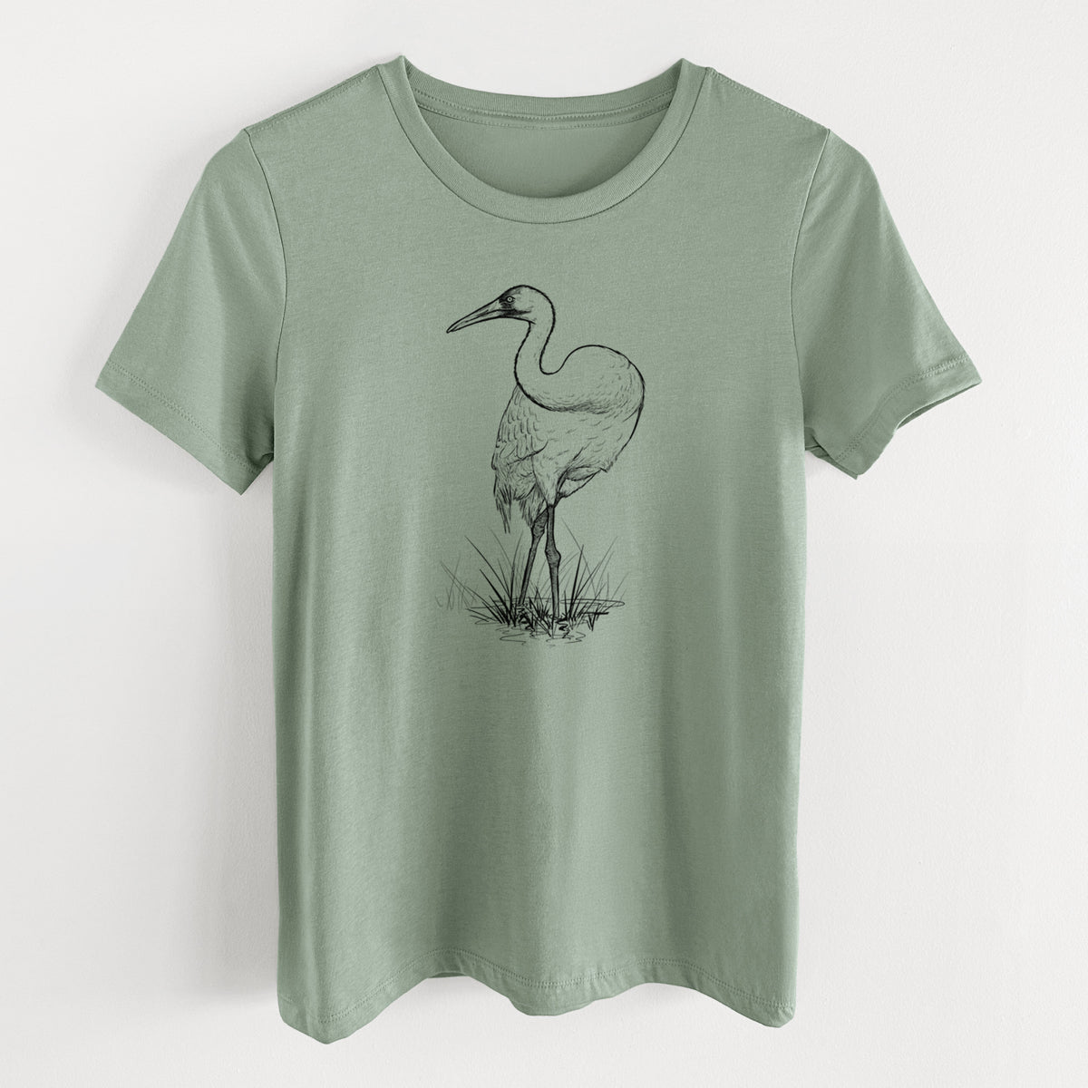 Sage green women's relaxed fit cotton t-shirt laid flat, printed with a detailed black ink illustration of a whooping crane standing in grass.