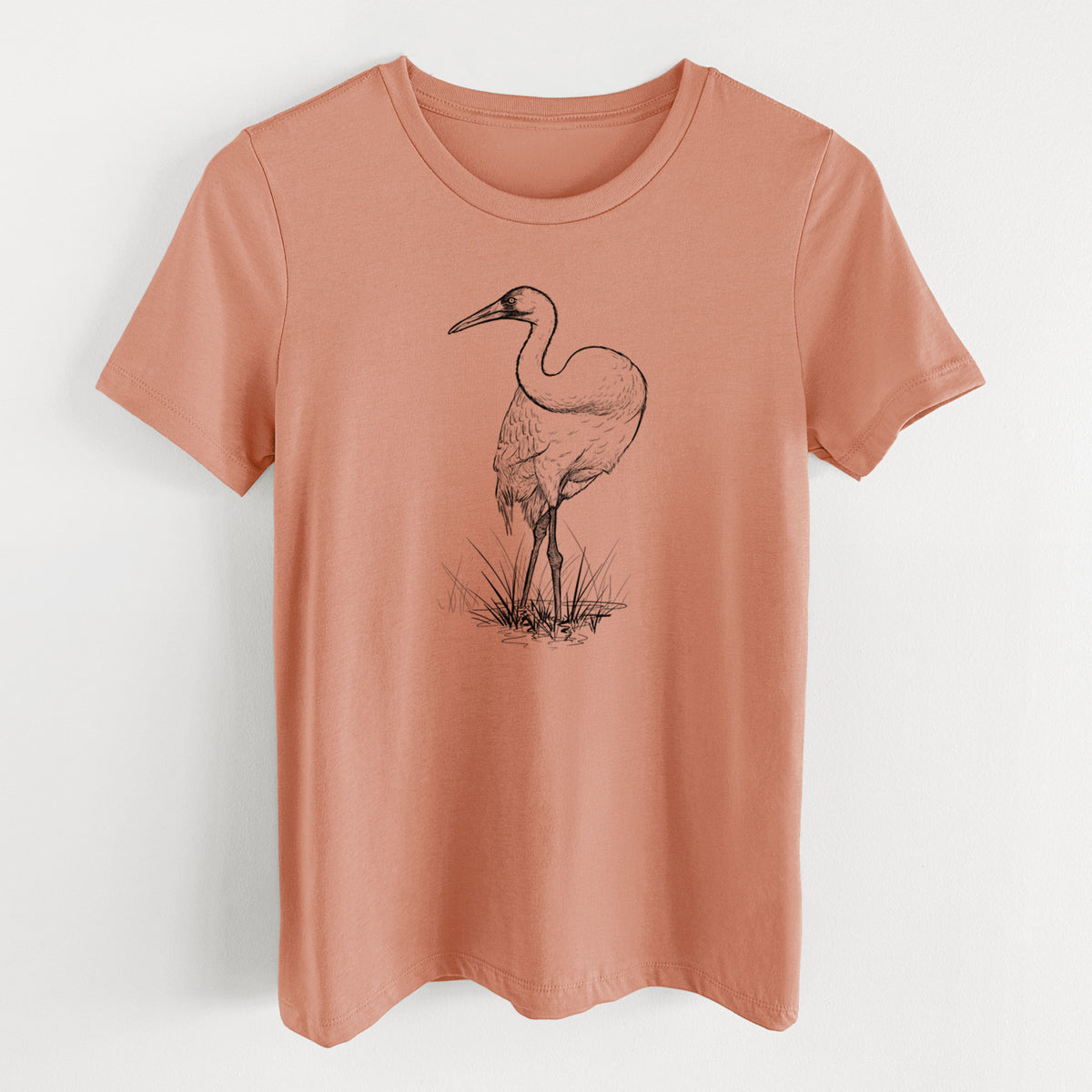 Terracotta orange women's relaxed fit cotton t-shirt laid flat, printed with a detailed black ink illustration of a whooping crane standing in grass.