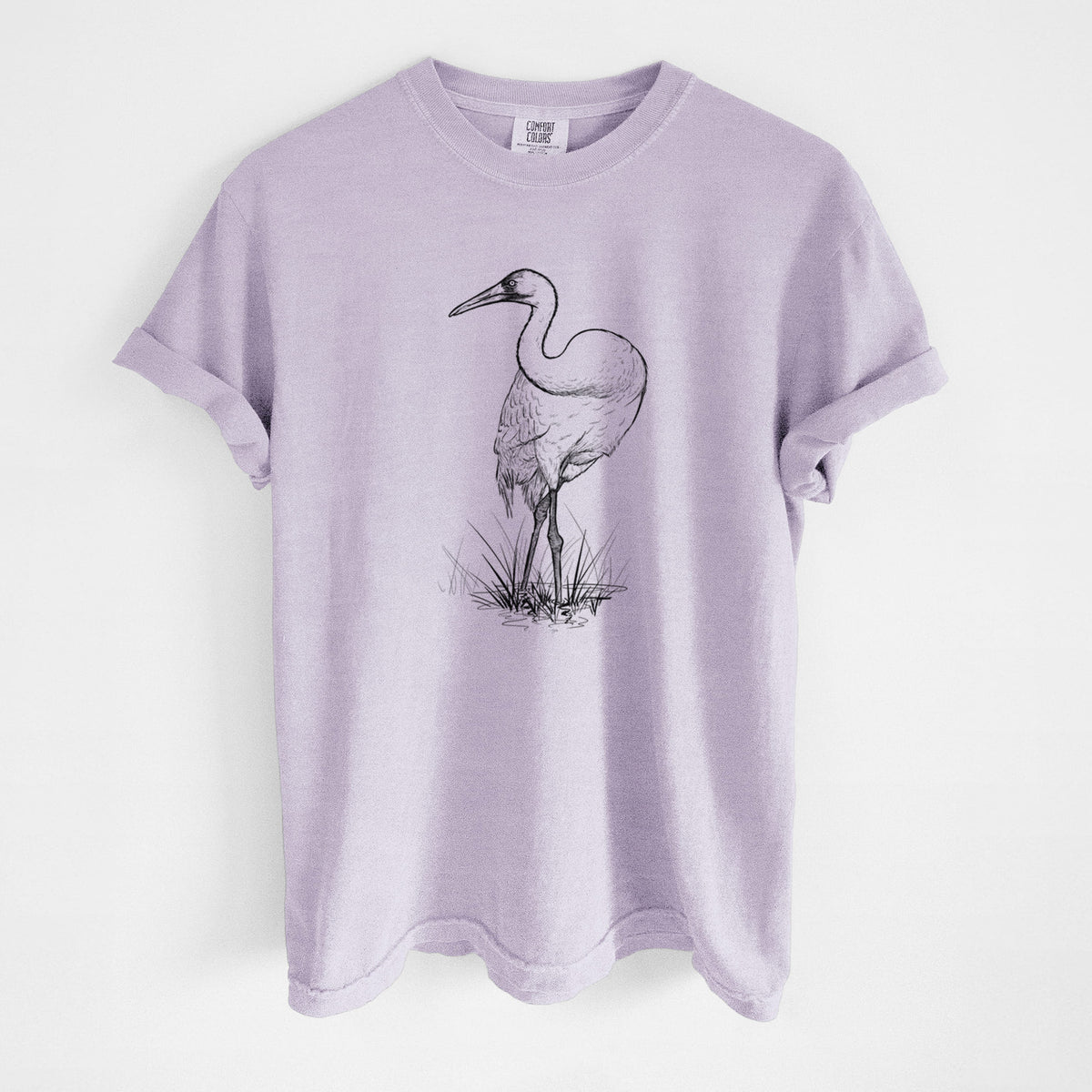 Orchid purple Comfort Colors t-shirt laid flat, printed with a detailed black ink illustration of a whooping crane standing in grass.