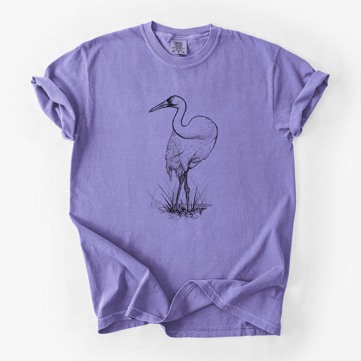 Violet purple Comfort Colors t-shirt laid flat, printed with a detailed black ink illustration of a whooping crane standing in grass.