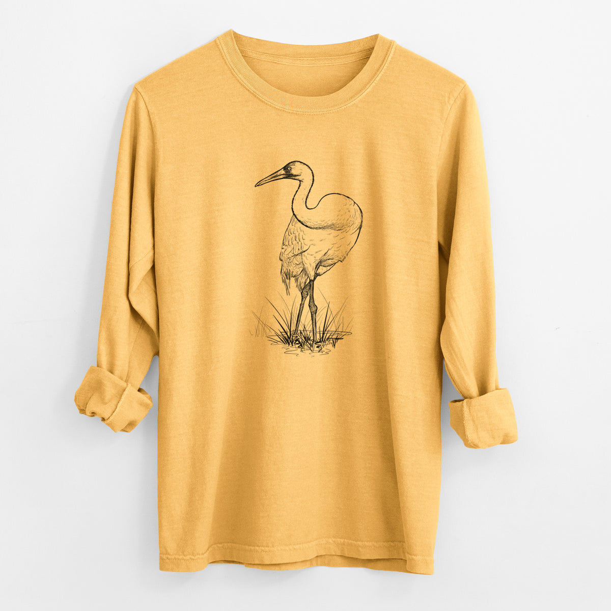 Golden wheat yellow Comfort Colors long sleeve shirt laid flat with the cuffs rolled, printed with a detailed black ink illustration of a whooping crane standing in grass.