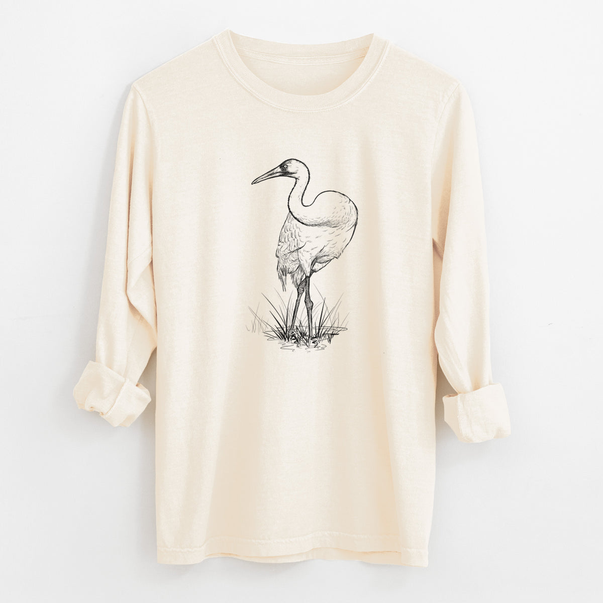 Ivory Comfort Colors long sleeve shirt laid flat with the cuffs rolled, printed with a detailed black ink illustration of a whooping crane standing in grass.