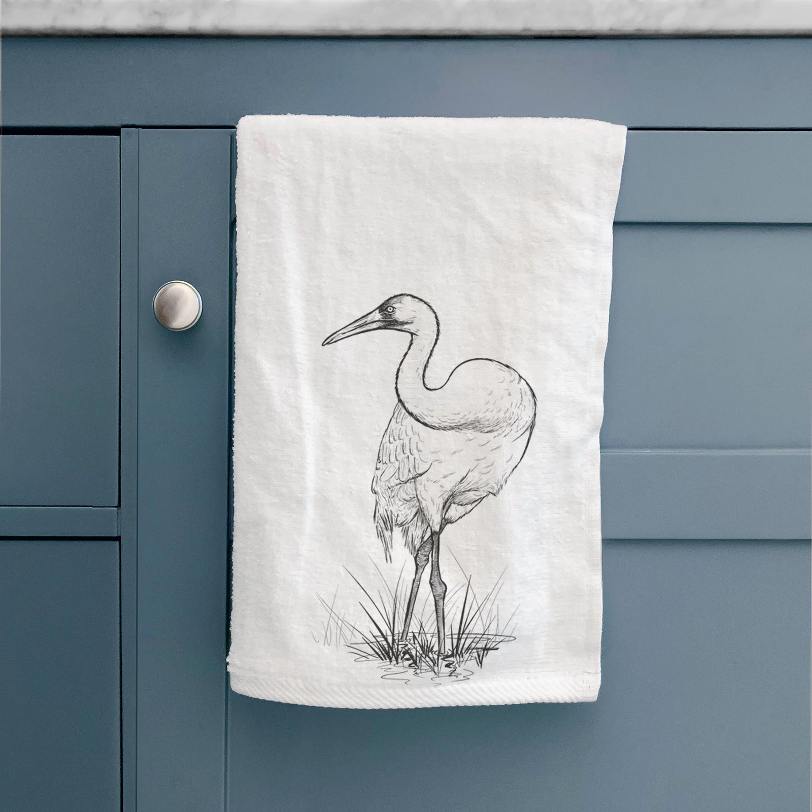 White hand towel printed with a detailed black ink illustration of a whooping crane standing in grass.