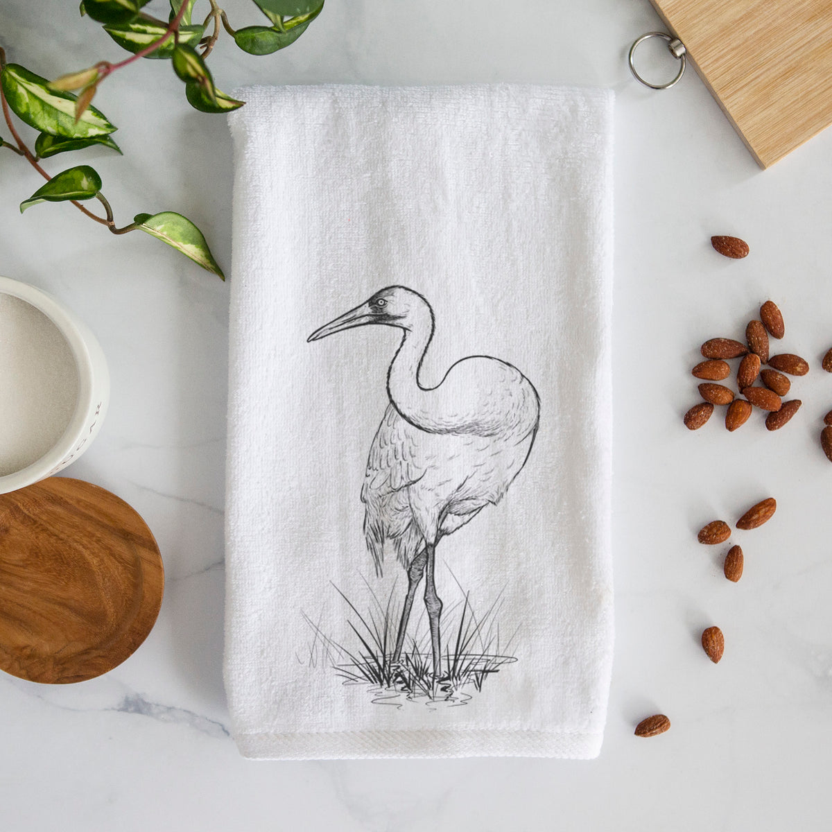 White hand towel printed with a detailed black ink illustration of a whooping crane standing in grass.