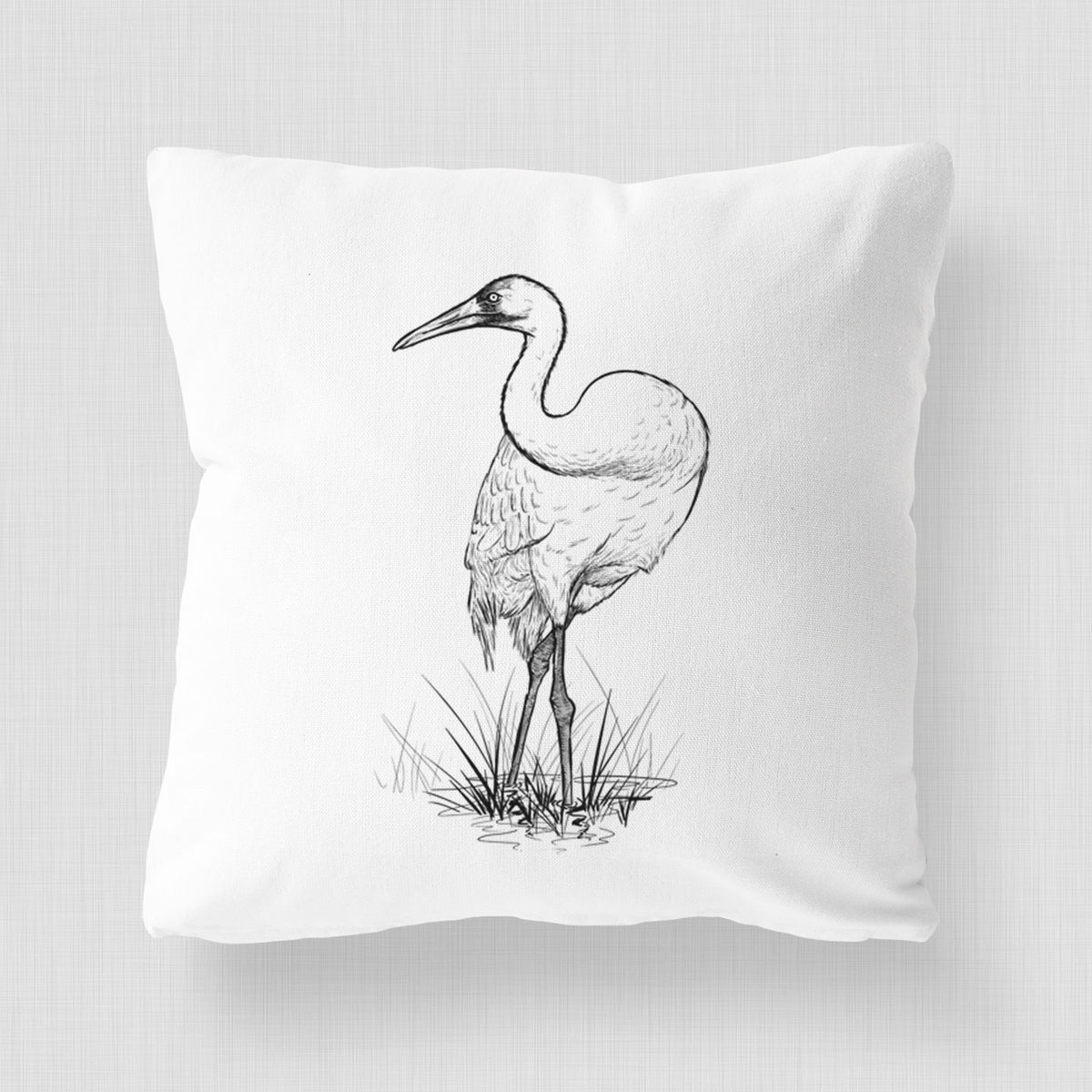 White pillow cover printed with a detailed black ink illustration of a whooping crane standing in grass.
