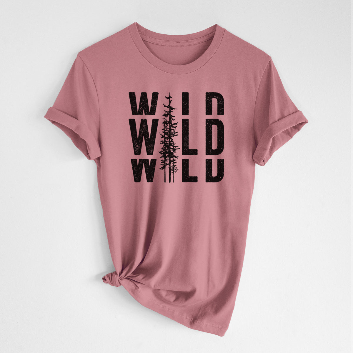 Mauve pink lightweight cotton t-shirt laid flat with the sleeves rolled, printed with bold black text reading WILD stacked three times, with a tall pine tree forming the letter I.